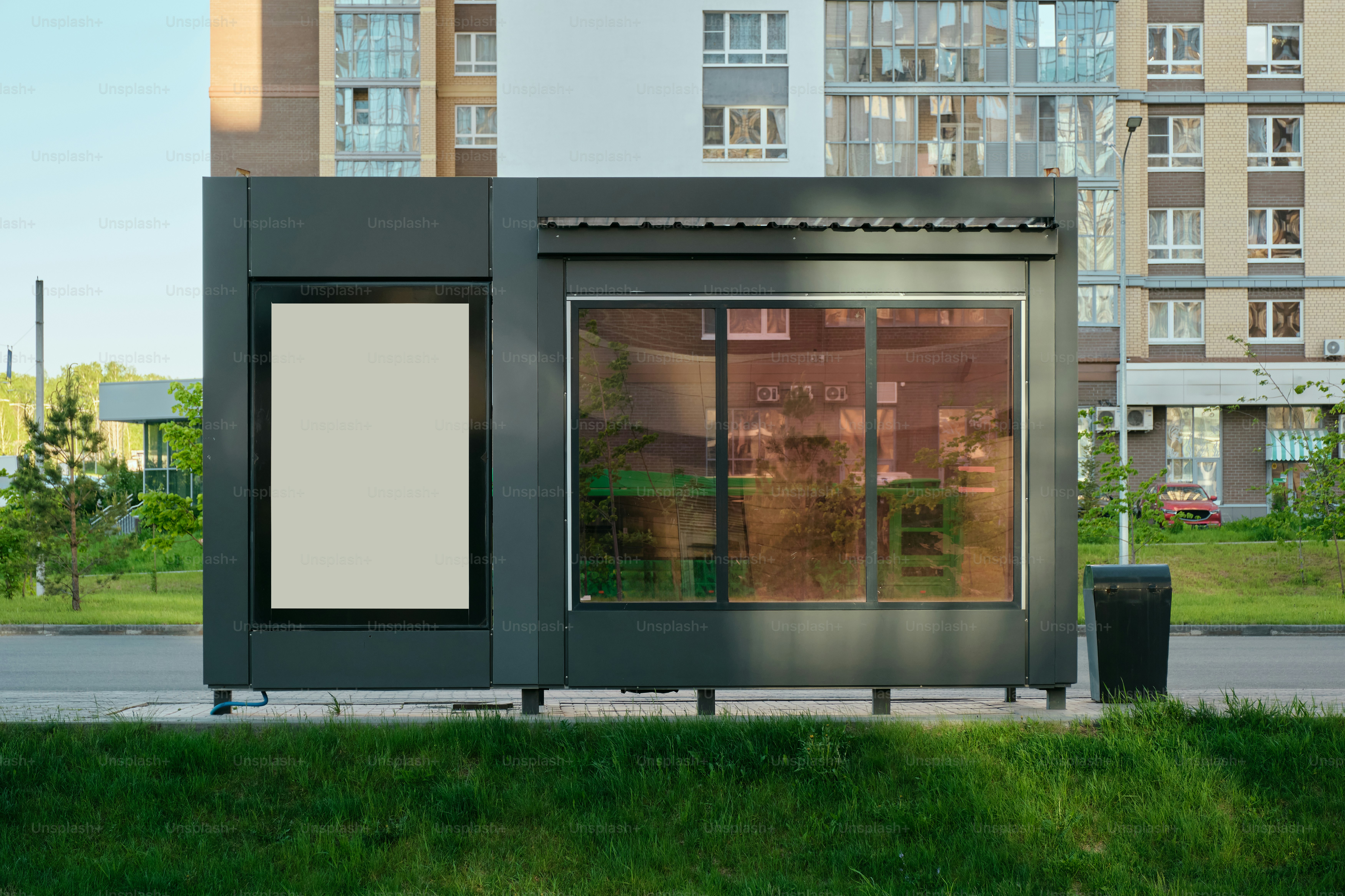 A modern kiosk stands in front of buildings.
