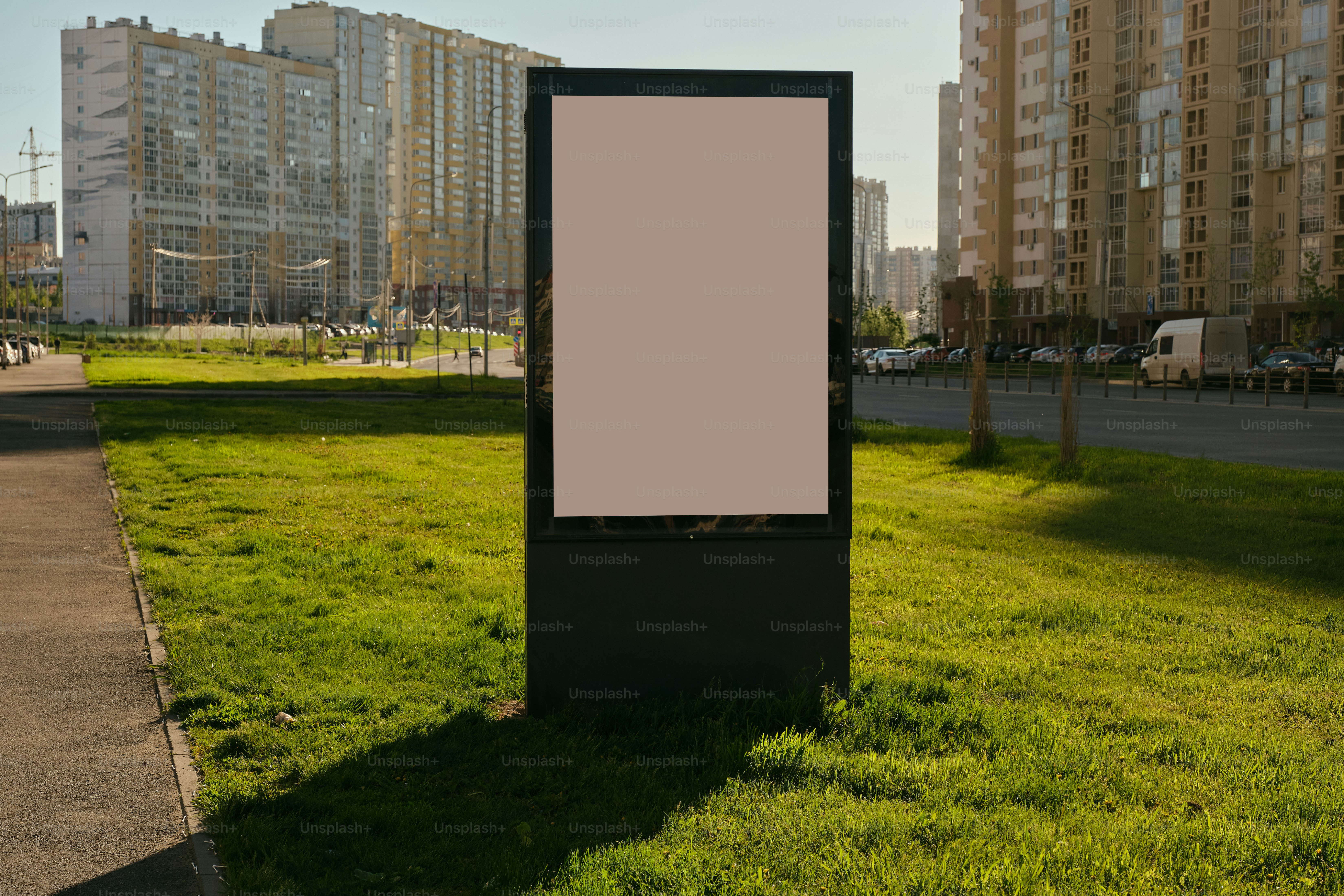 A blank billboard stands amidst green grass.