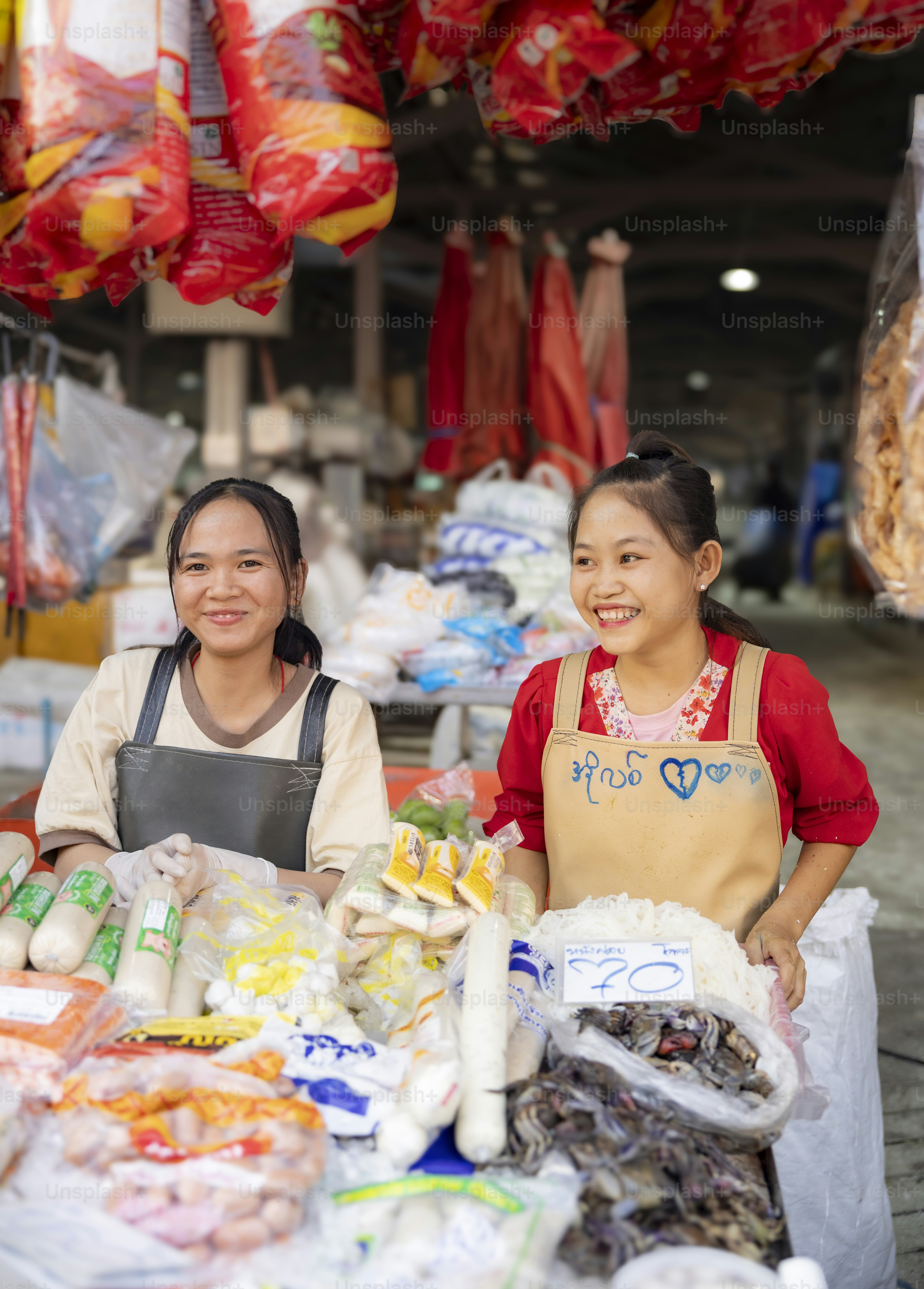 Two women smile while working at a food market.