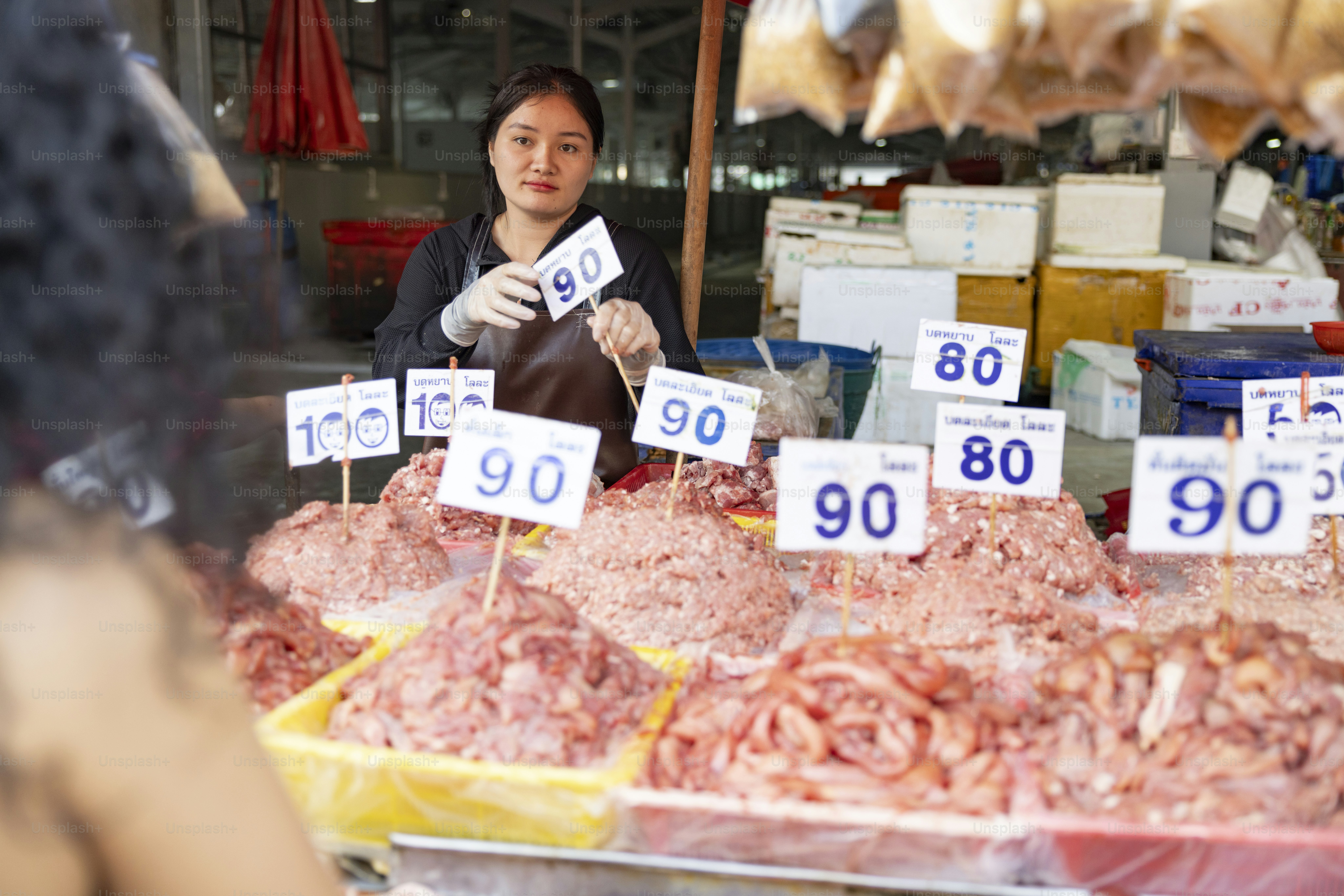A vendor sells meat with prices displayed.