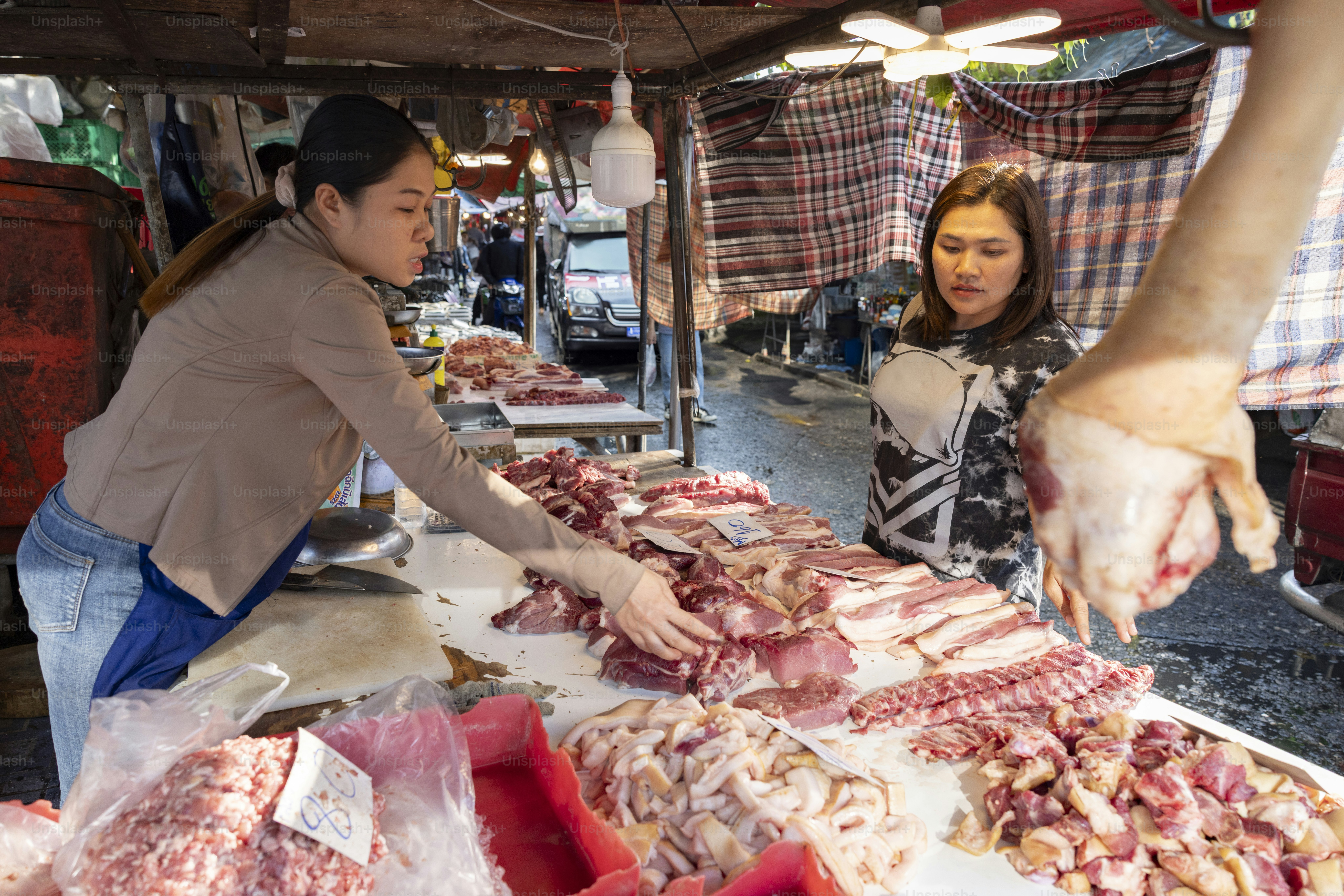 A butcher prepares meat for customers at a market. photo – Food Image ...