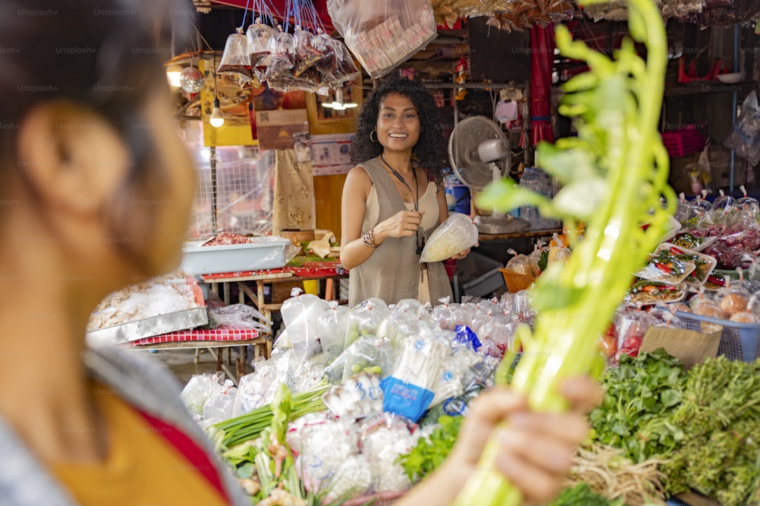 Woman buys celery from a friendly vendor at a market.