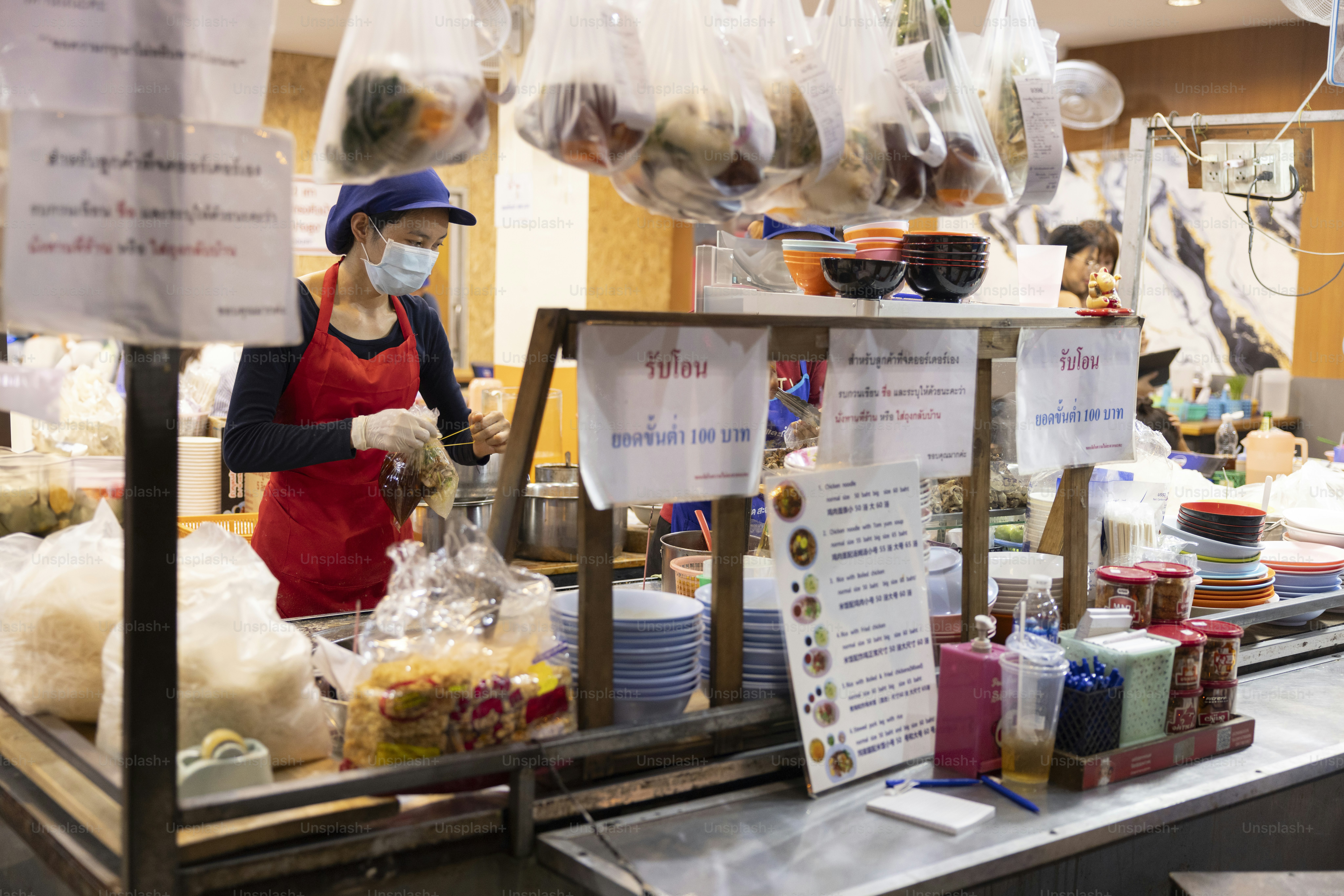 A food vendor prepares orders at a market stall.
