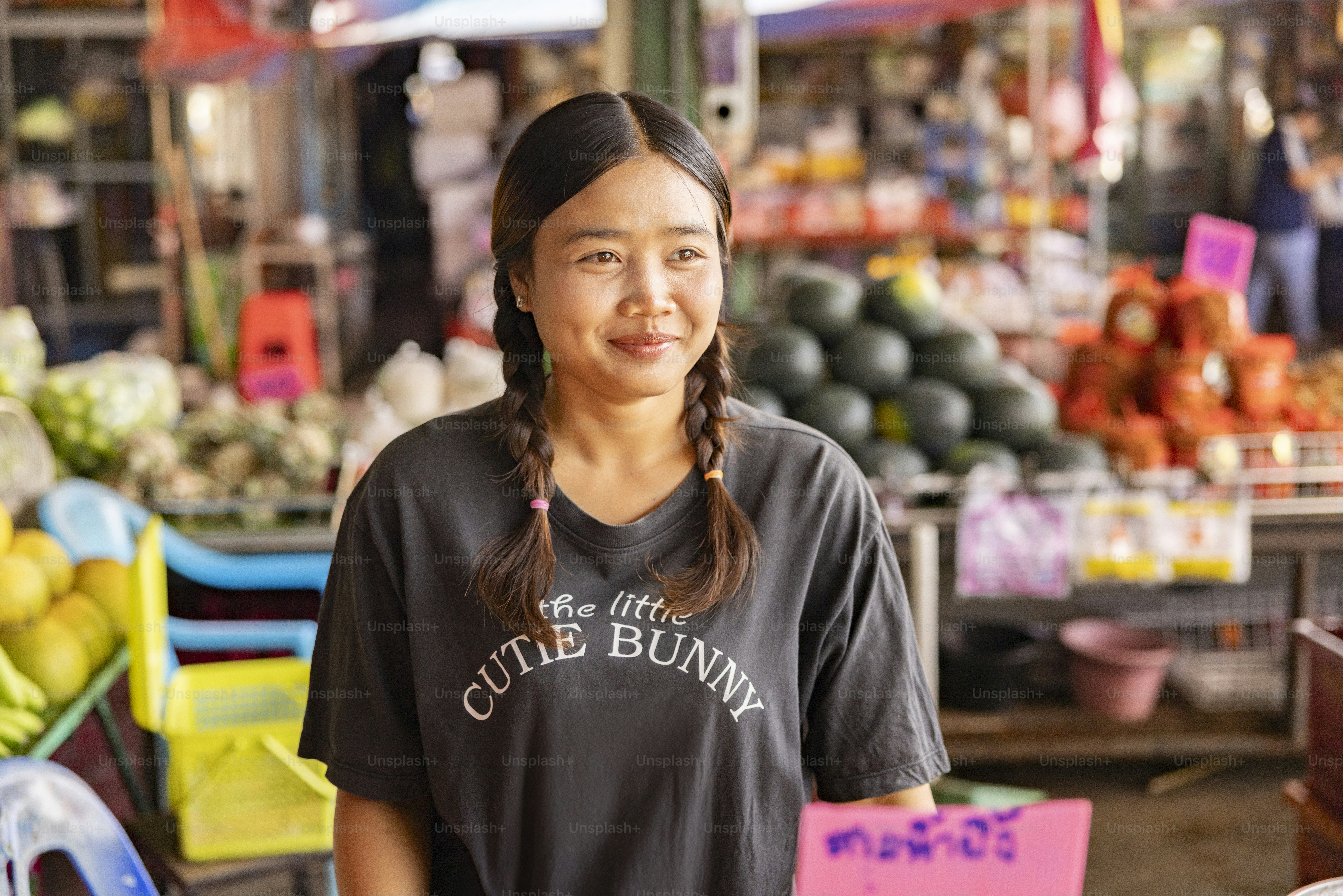 A woman smiles while standing at a market.