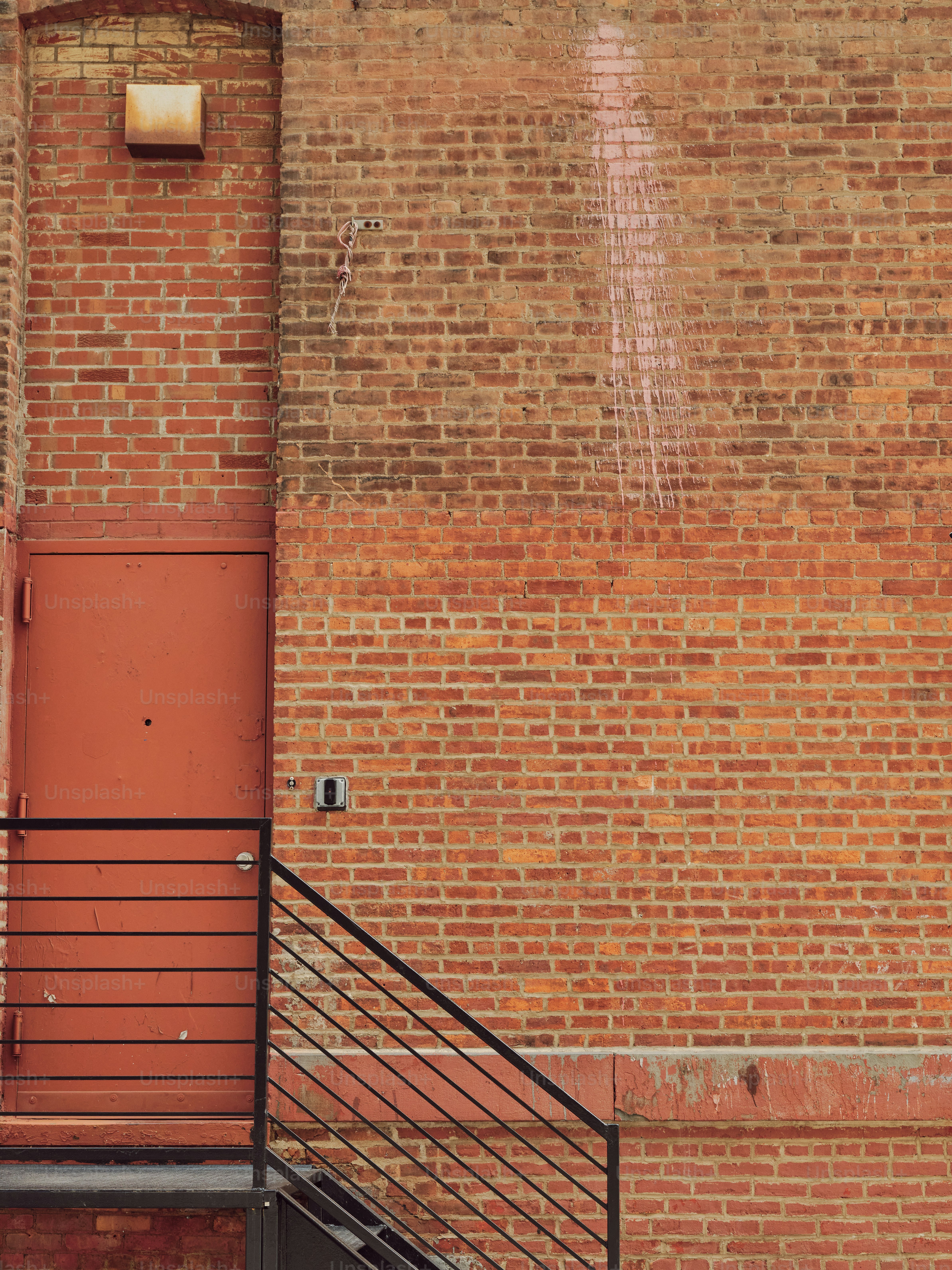 Eine Backsteinmauer und eine rote Tür.