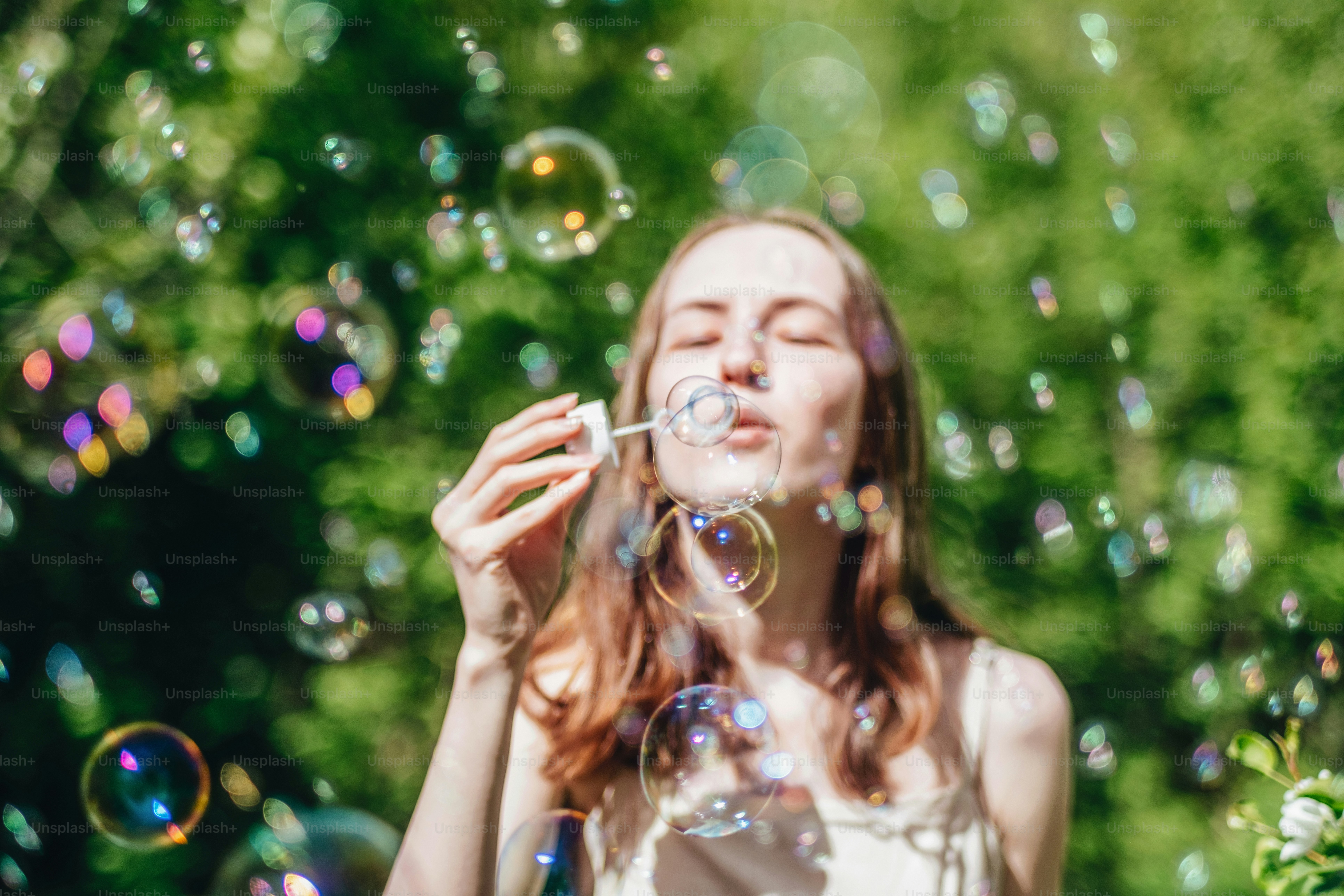 A young woman blows bubbles outside.