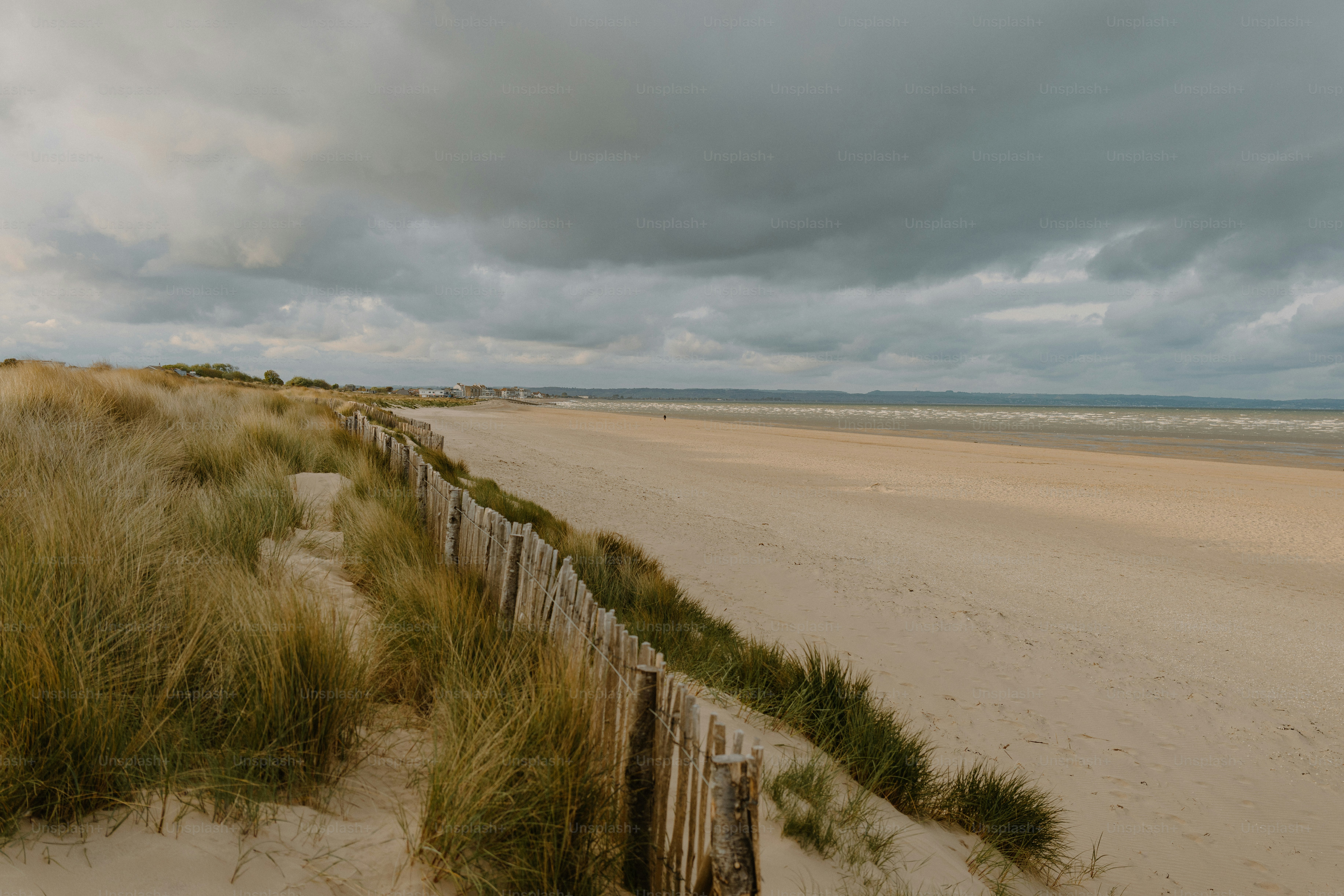 A beach sits under a moody, cloudy sky.