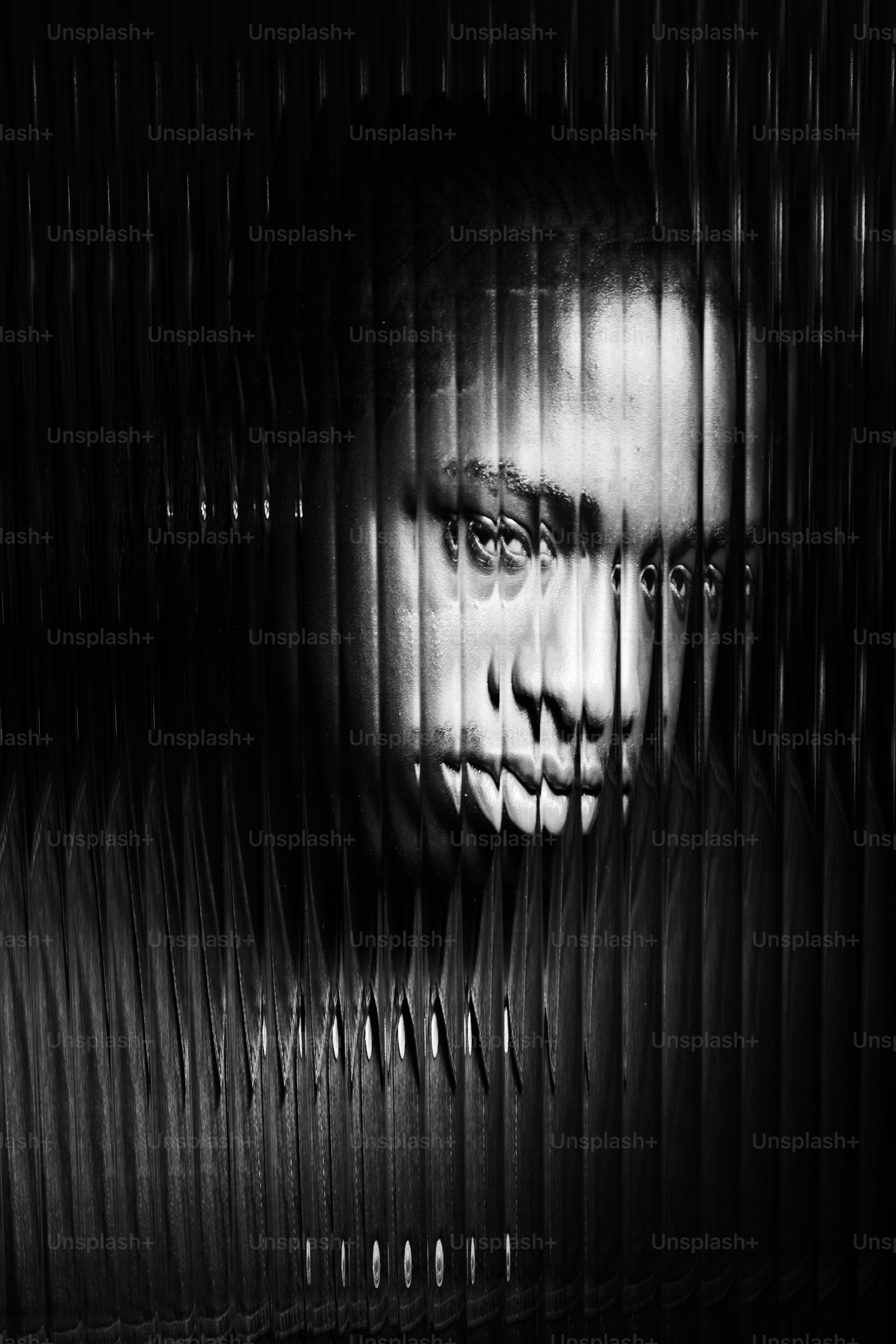 Wajah seorang pria, terfragmentasi oleh garis vertikal.