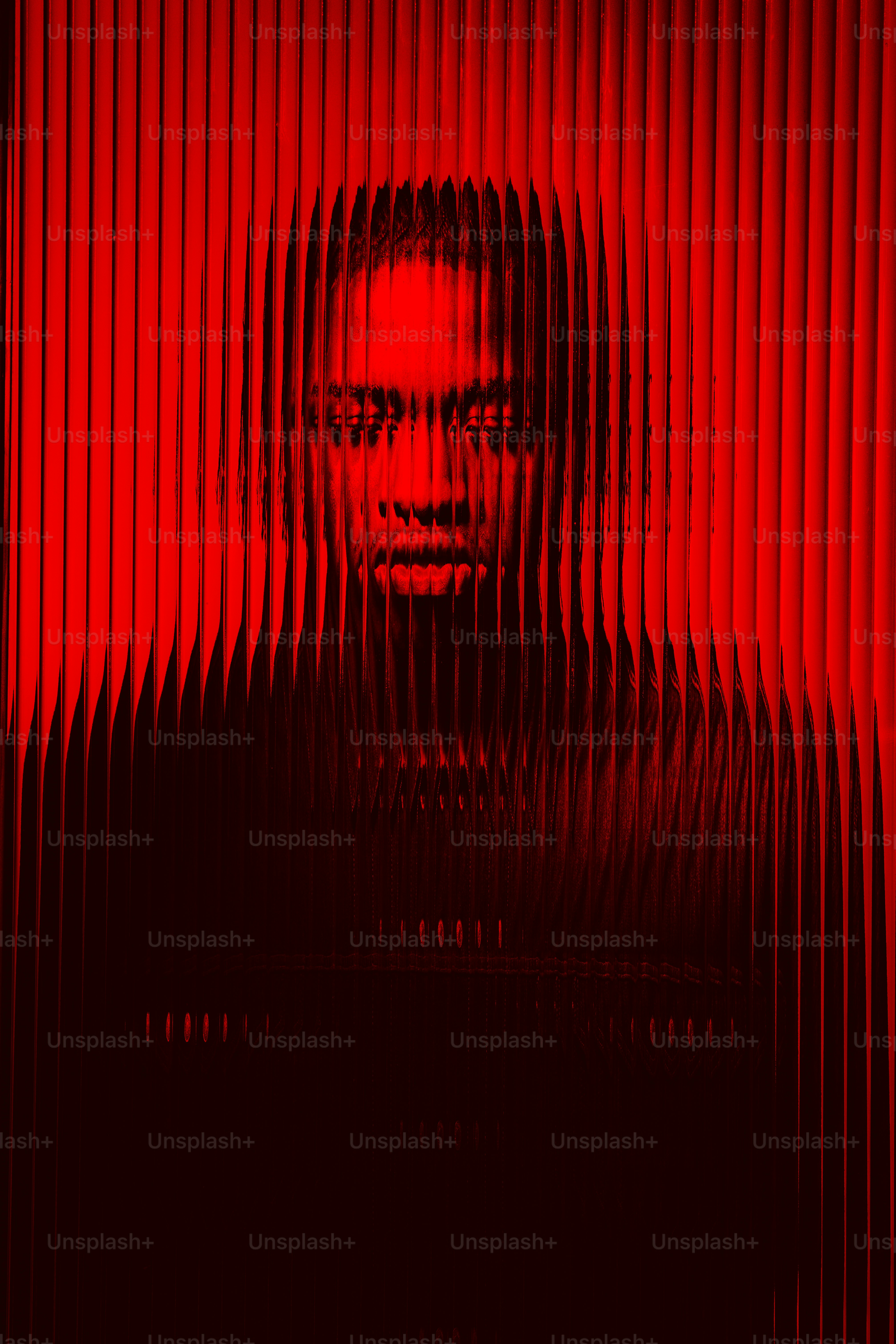 La silhouette d’une personne à travers des lignes verticales rouges.