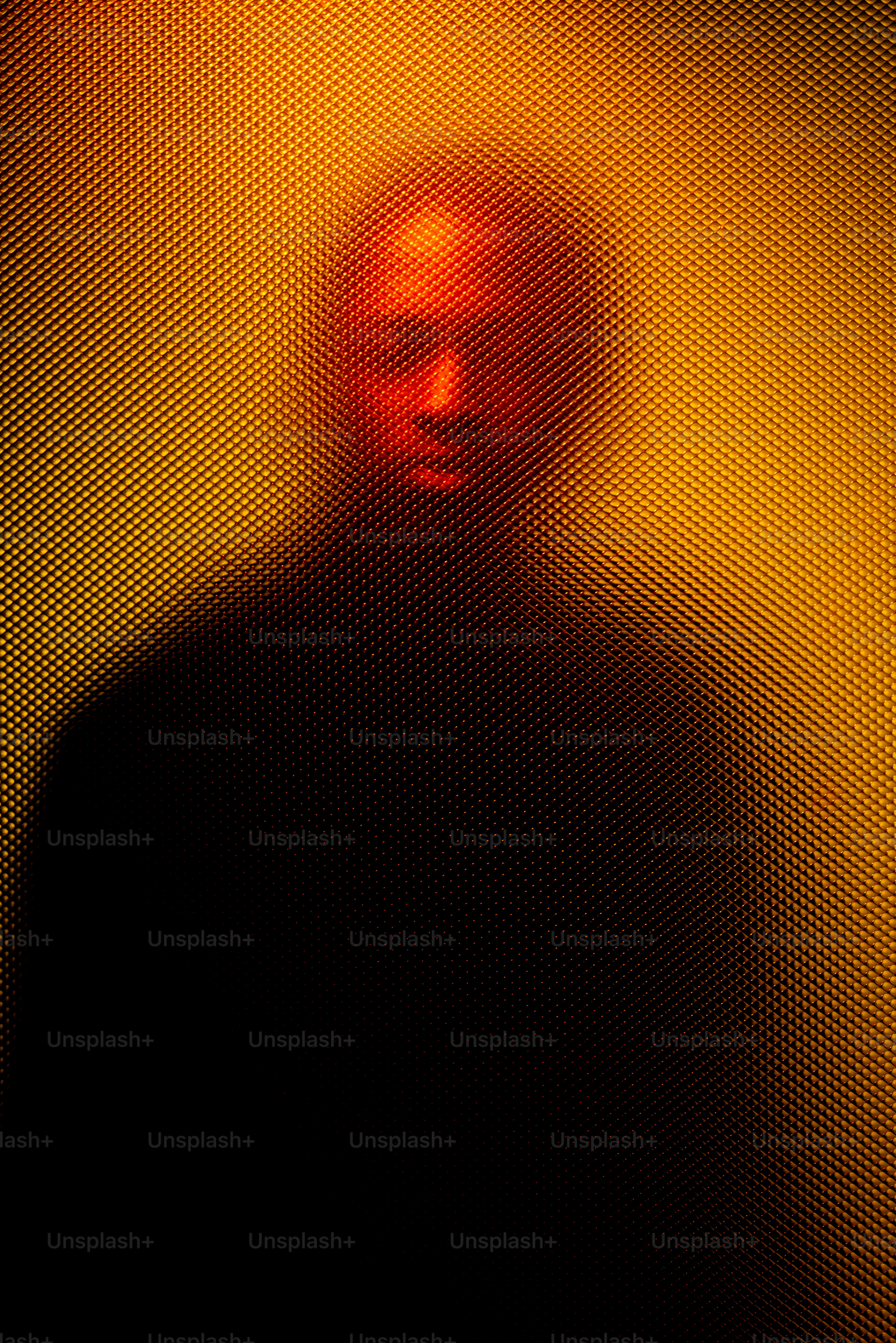 Uma silhueta é vista através de um pano de fundo amarelo texturizado.