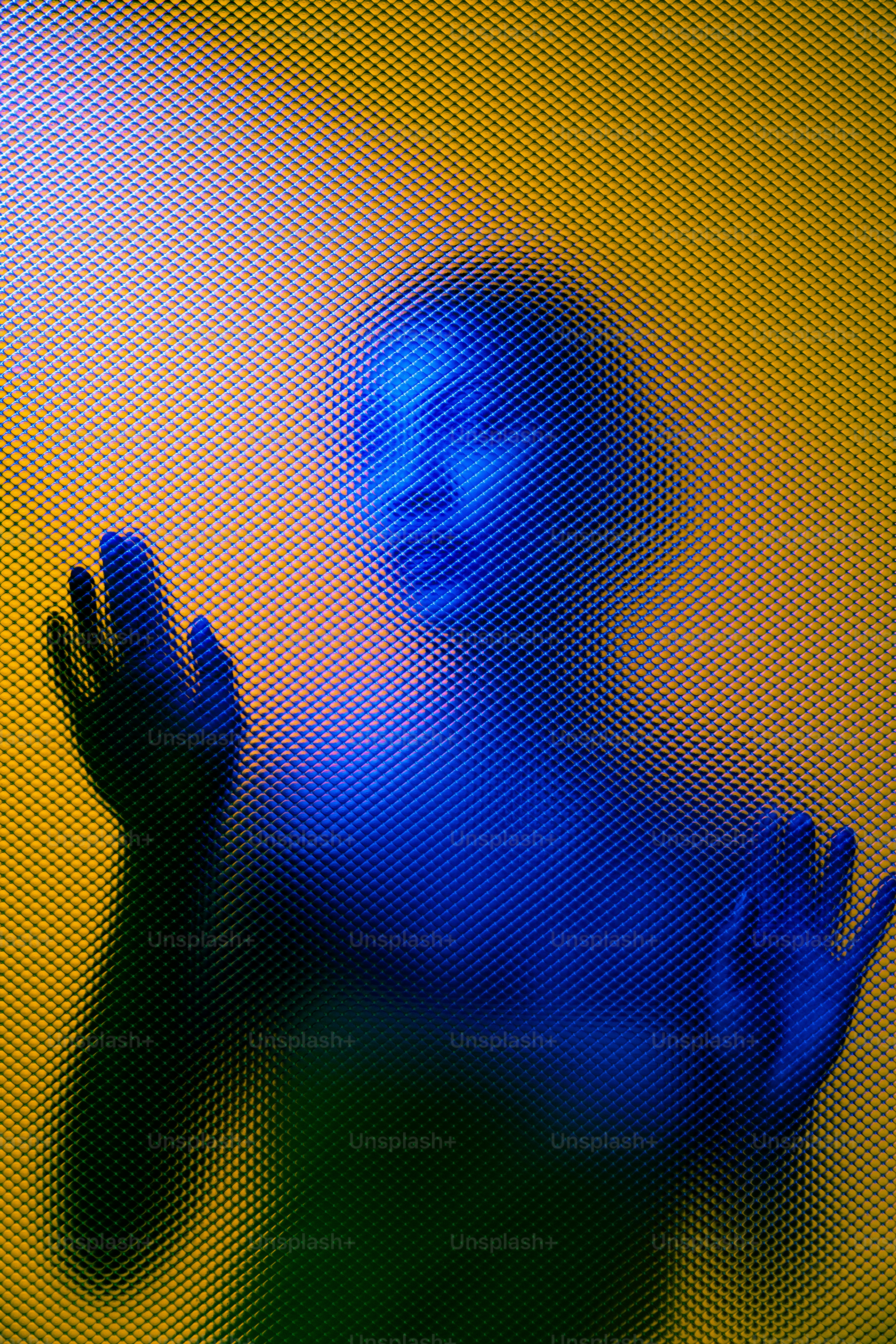 Siluet seseorang diterangi di balik kaca bertekstur.