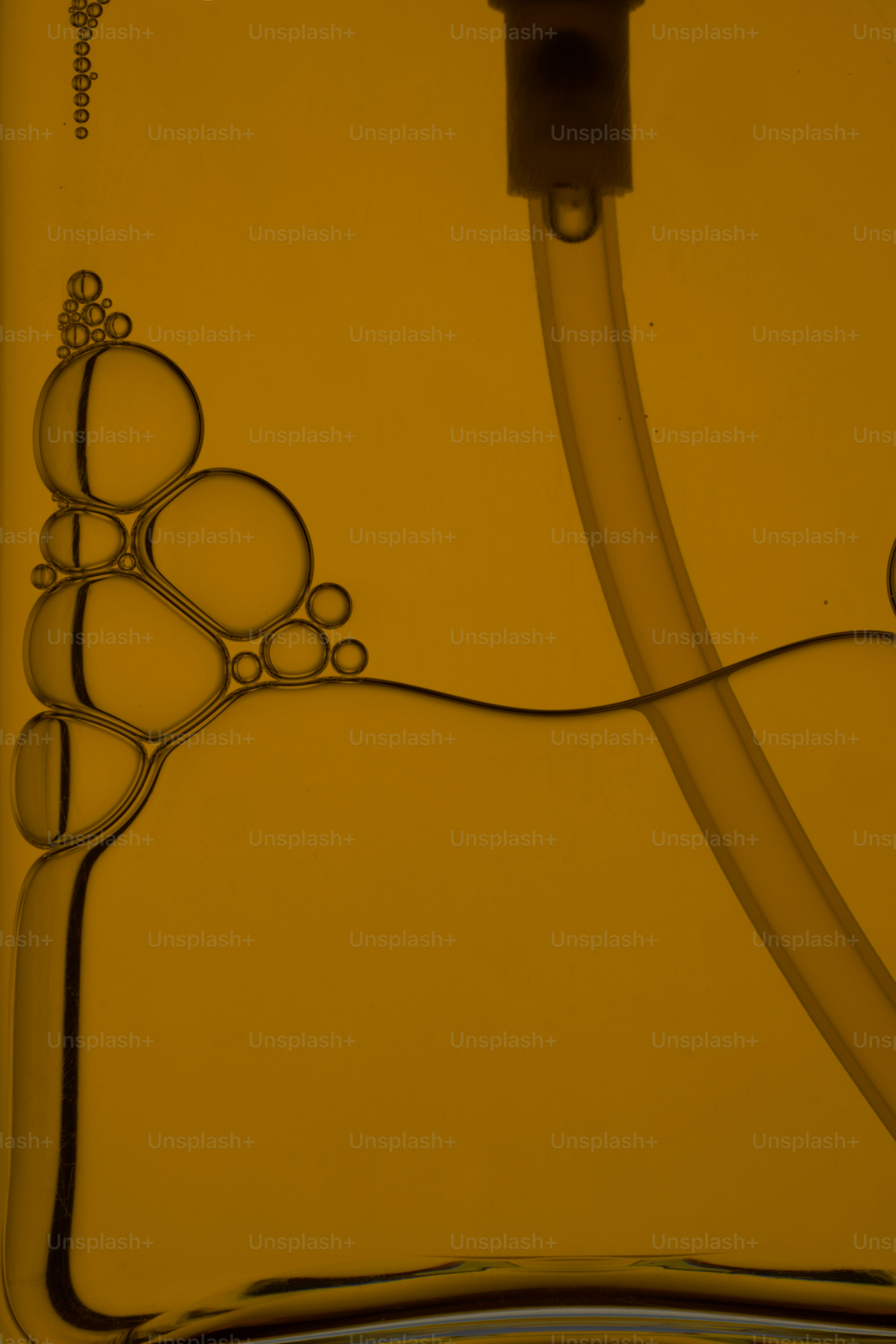 Bubbles and a tube are inside of a yellow liquid.