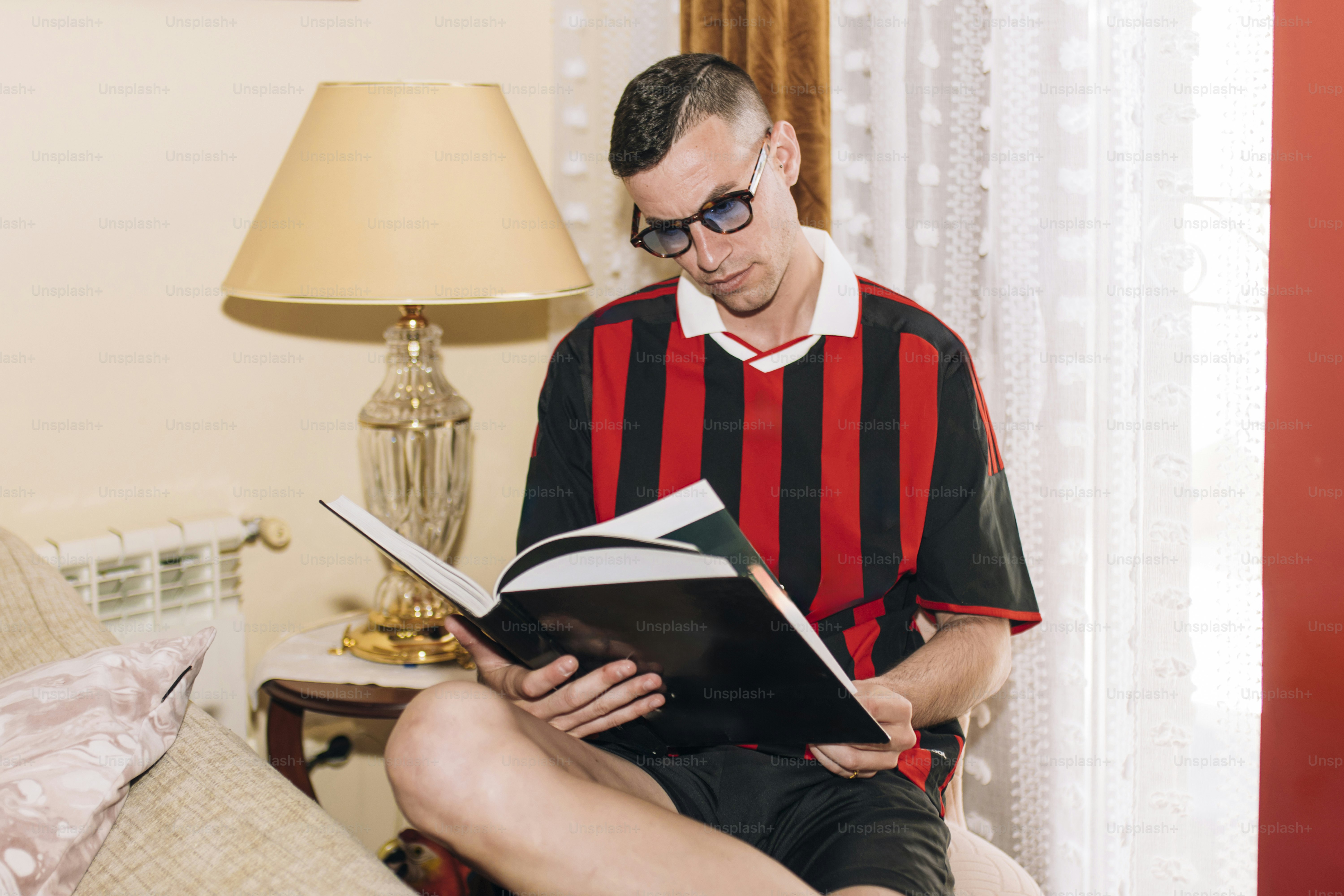 ランプの下で本を読んでいる男性。