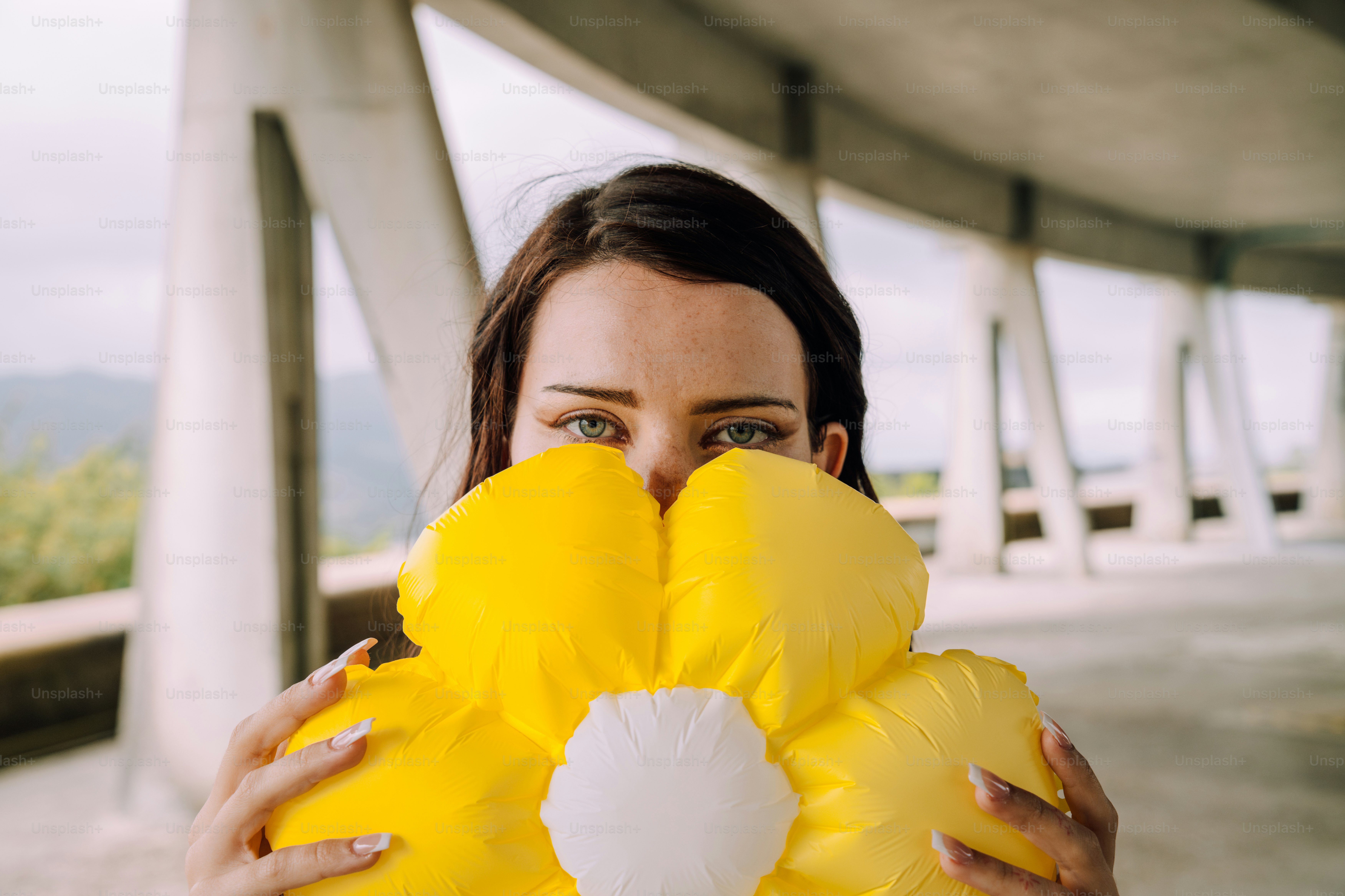 Woman hides her face behind a big yellow flower.