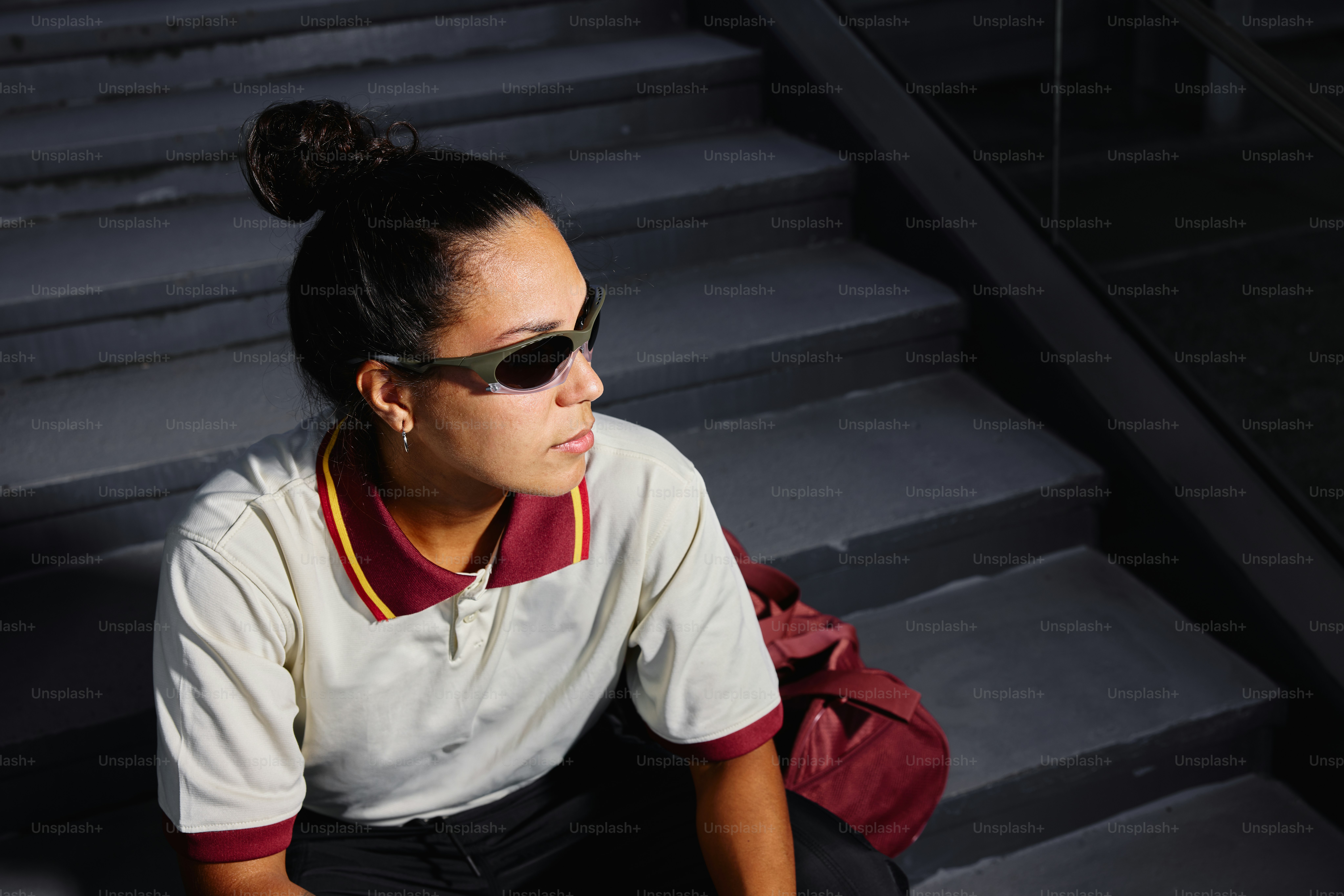 A person with sunglasses sits on the stairs.
