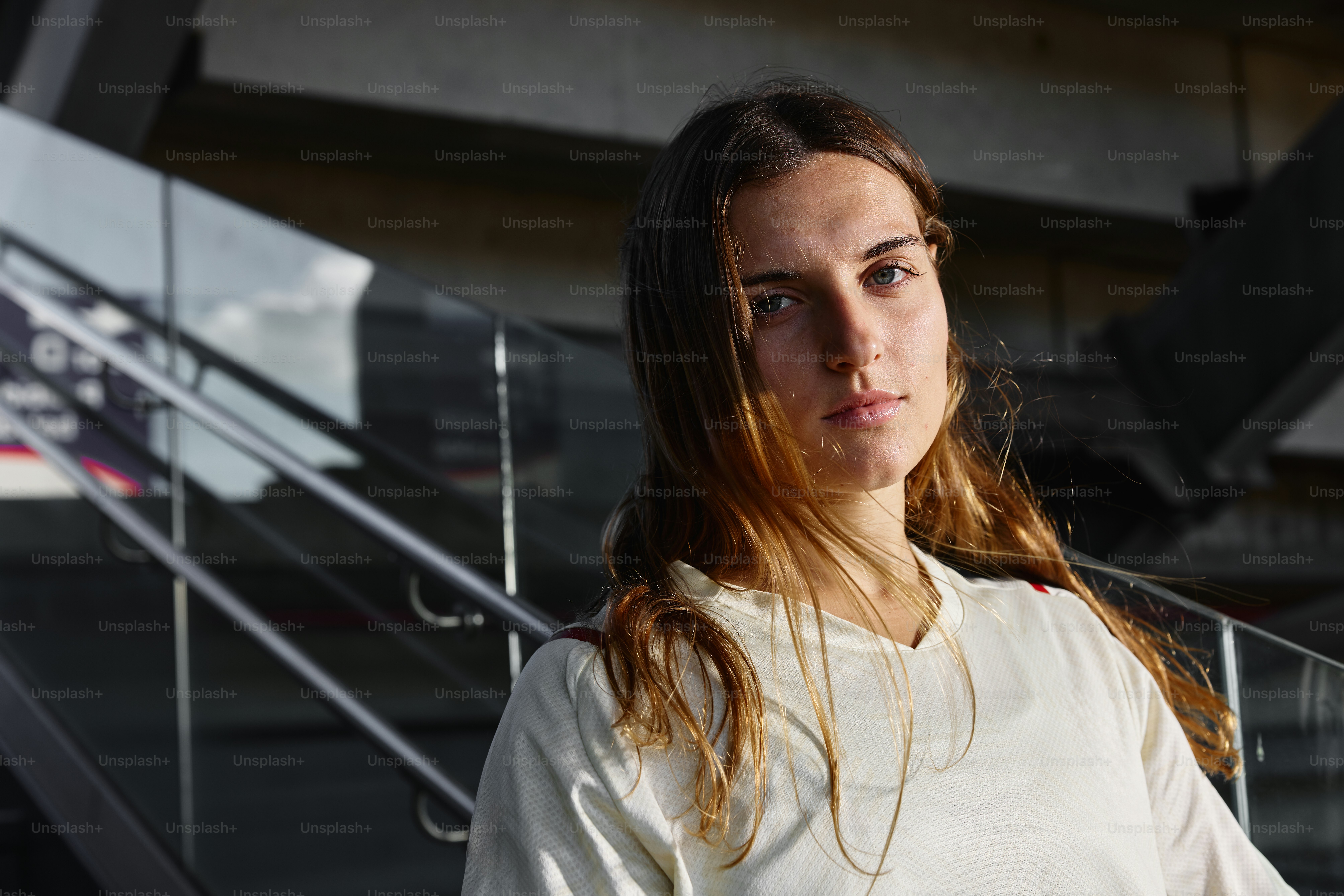 A young woman poses in front of stairs.