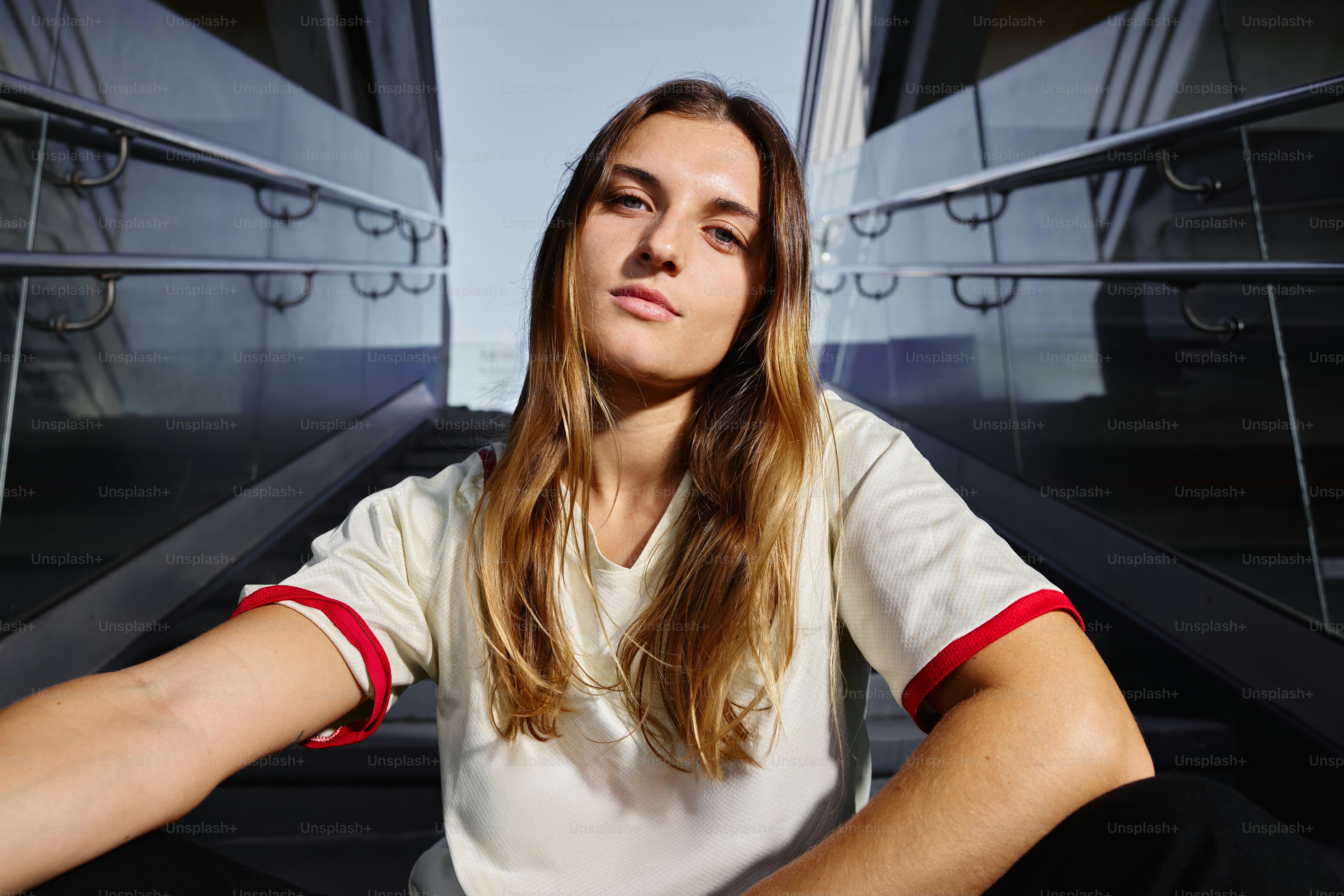 A young person poses below an escalator.