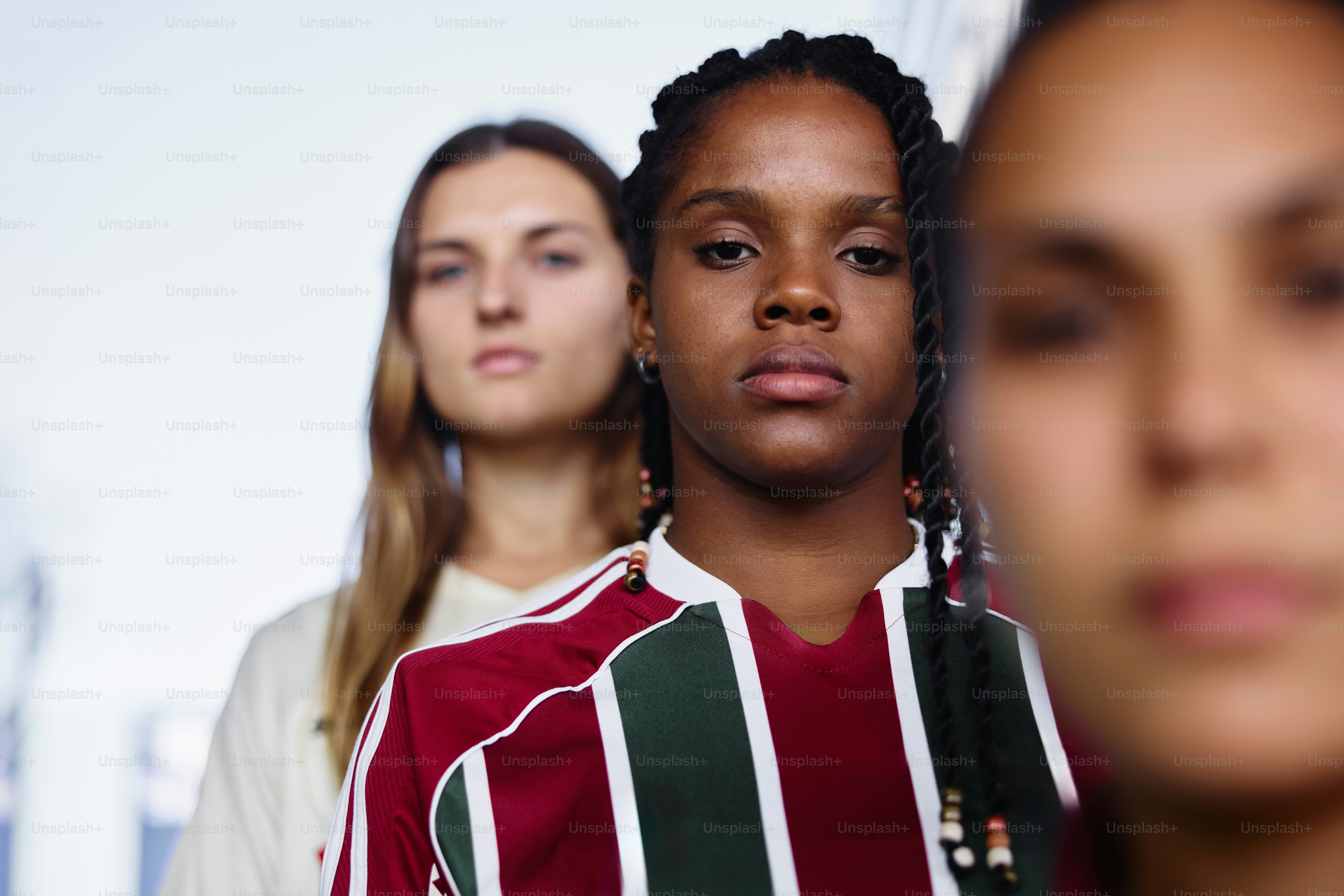 Three women stand in a row, looking forward.