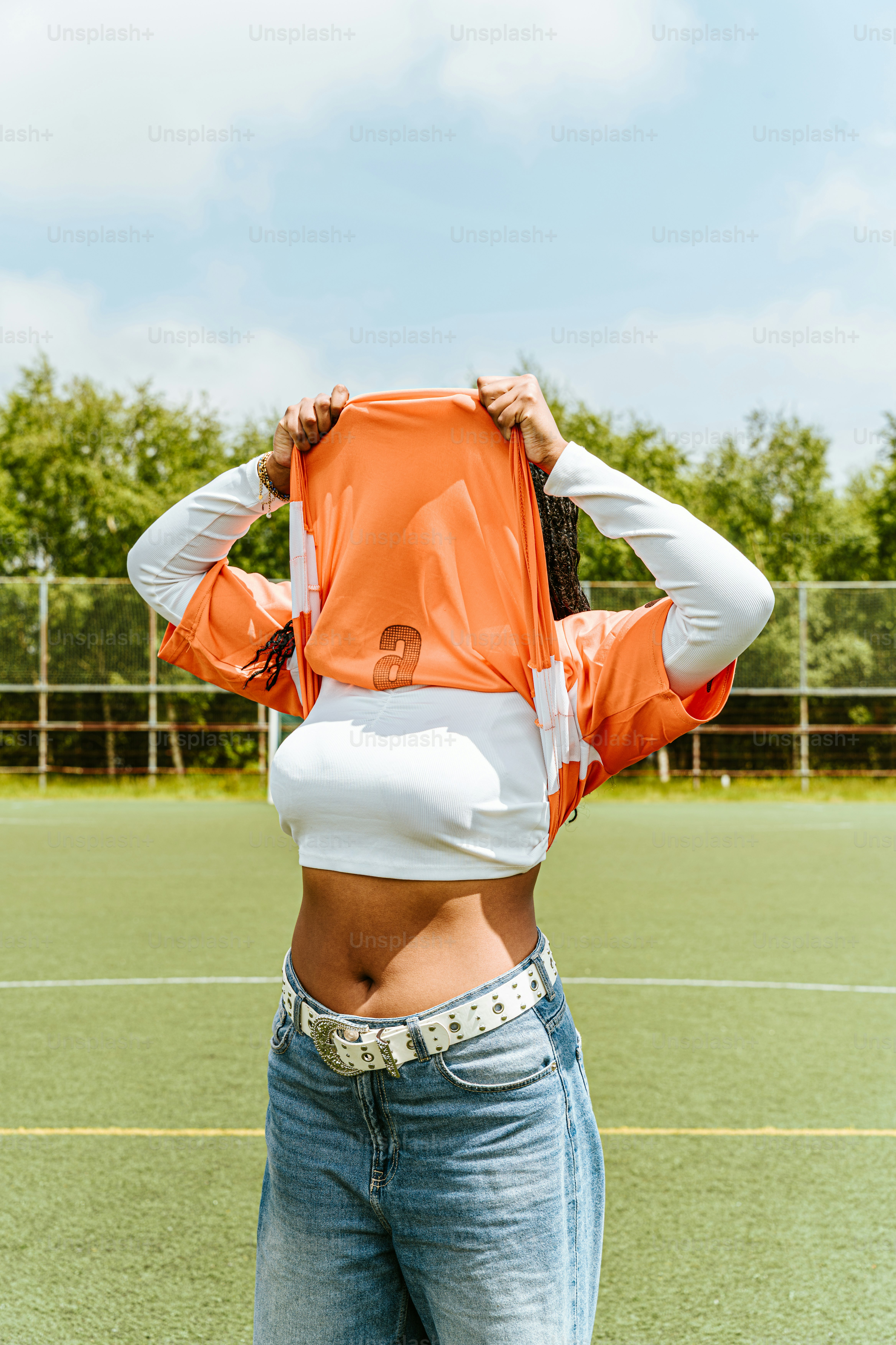 A person is pulling a shirt over their head.