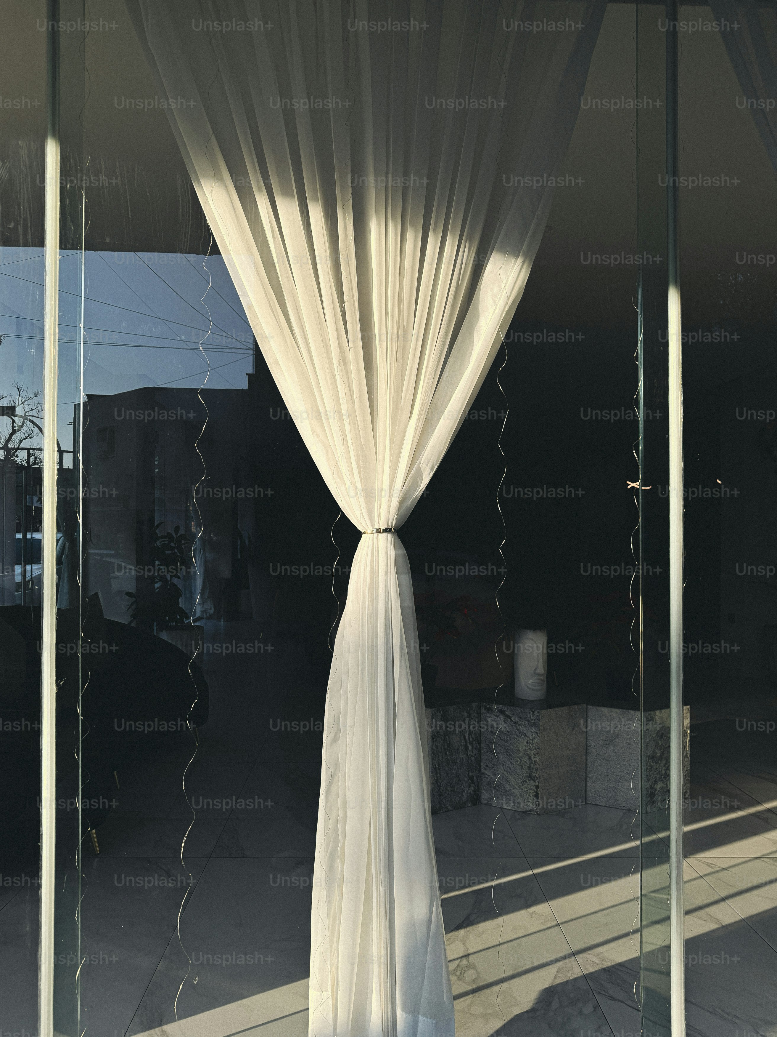 Sunlight shines through a white curtain.