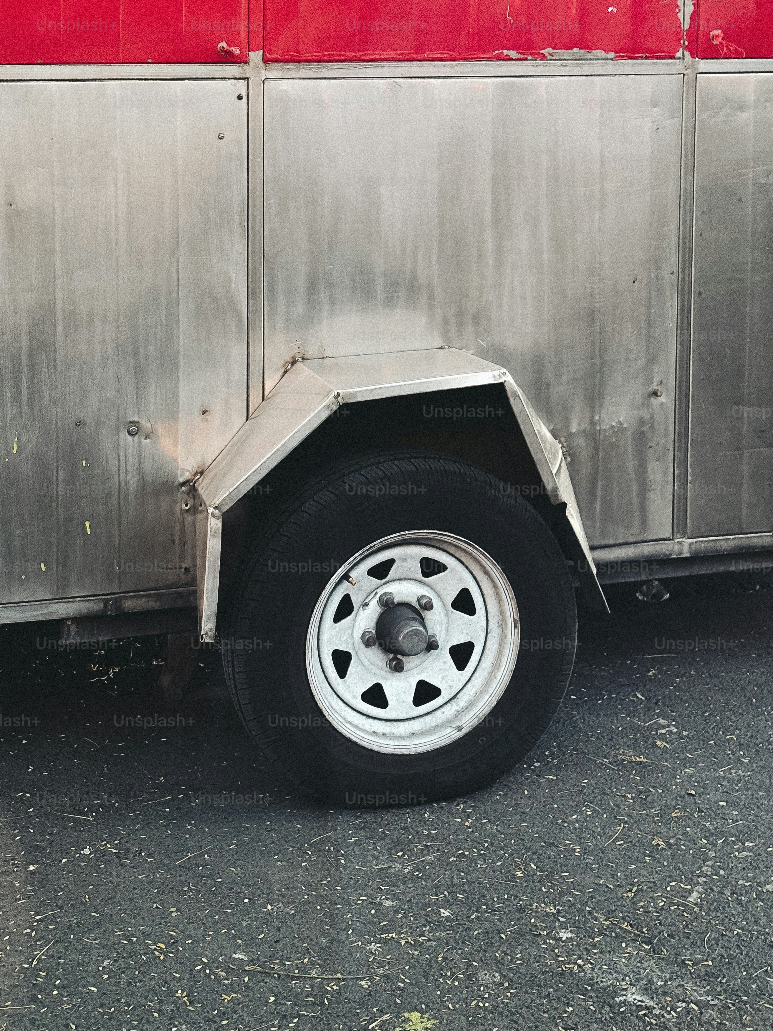 A trailer wheel sits against a metal wall.