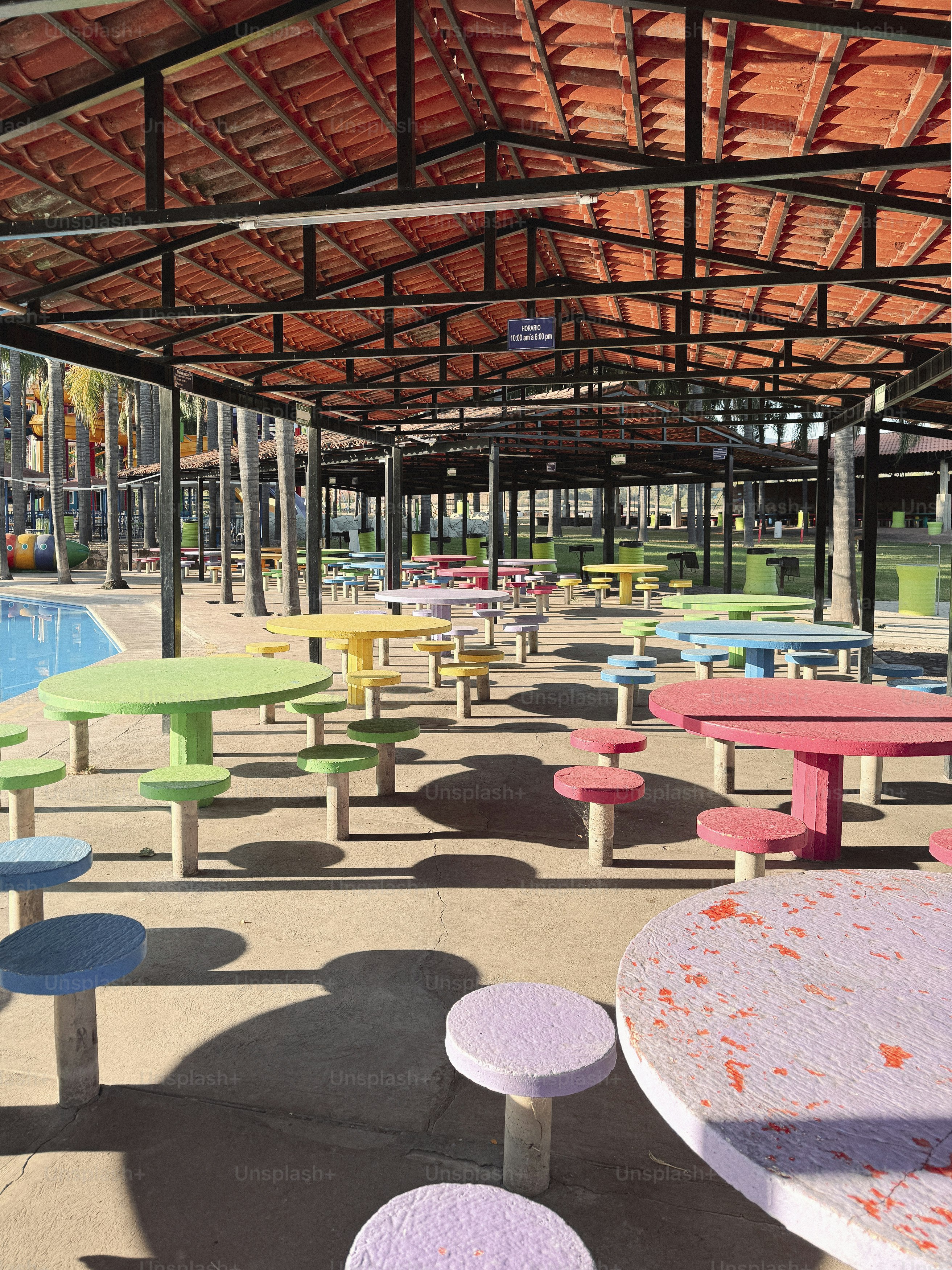 Outdoor eating area with colorful tables and shade.