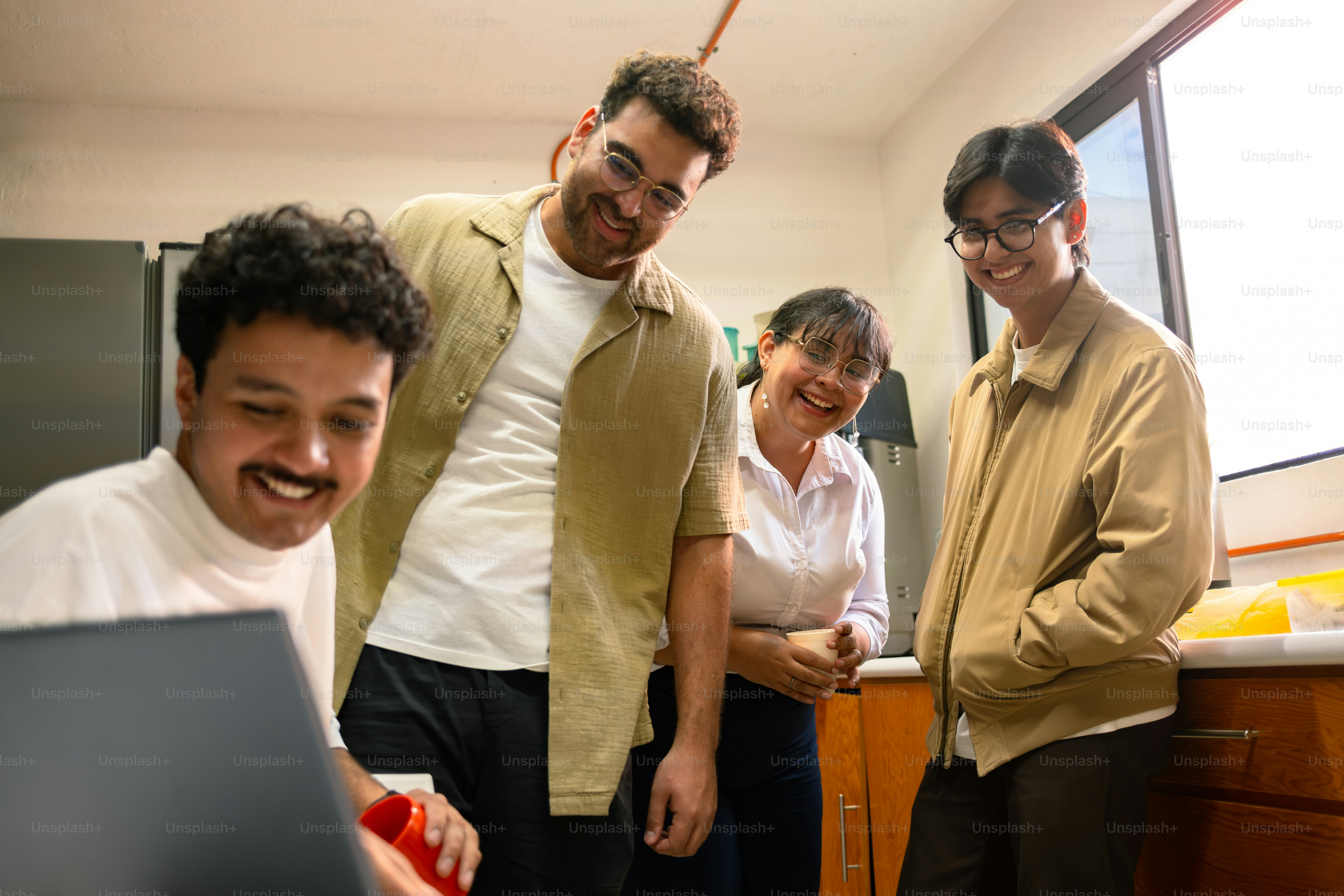 Four colleagues happily looking at a laptop screen.