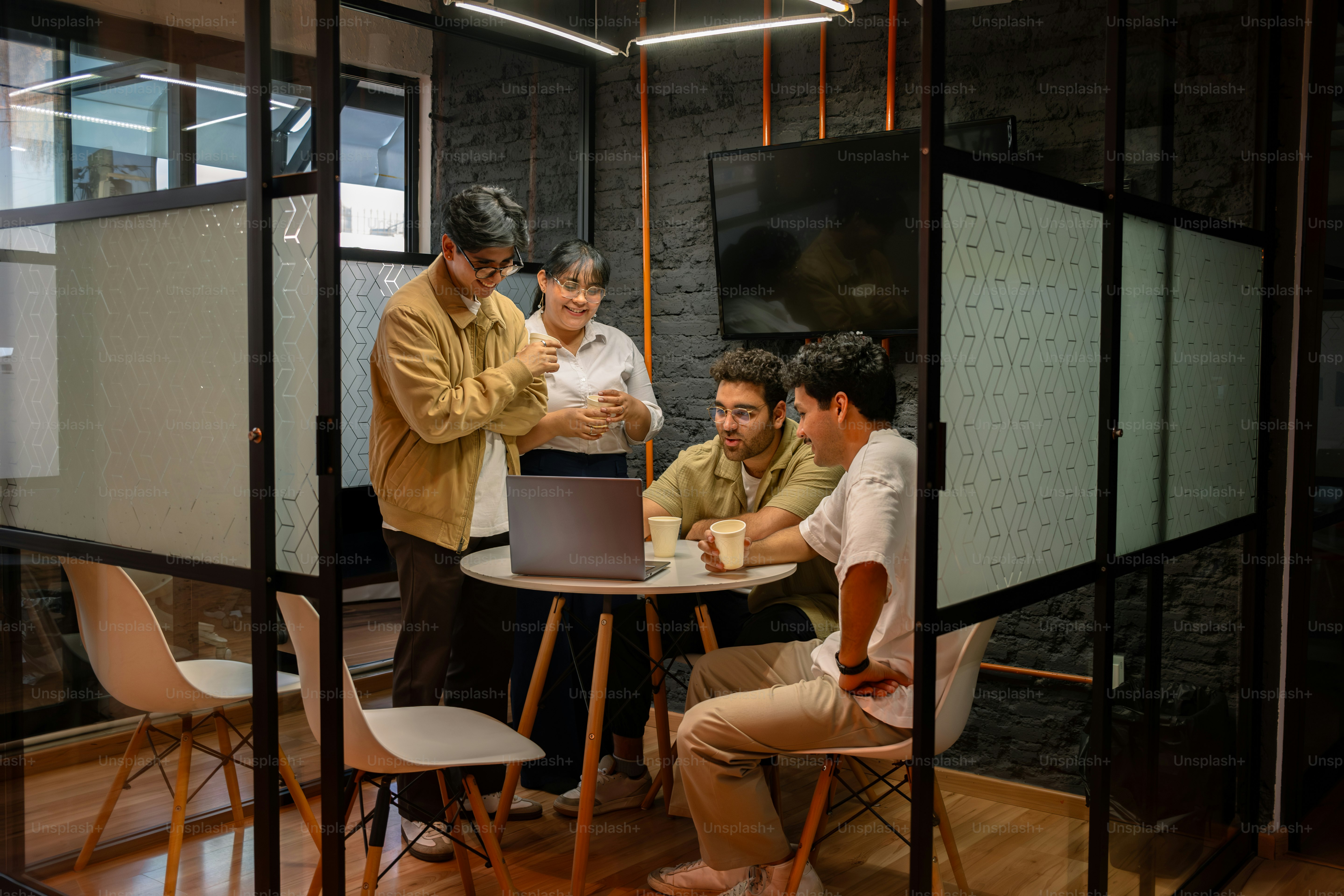 Colleagues collaborate around a laptop in a meeting room.