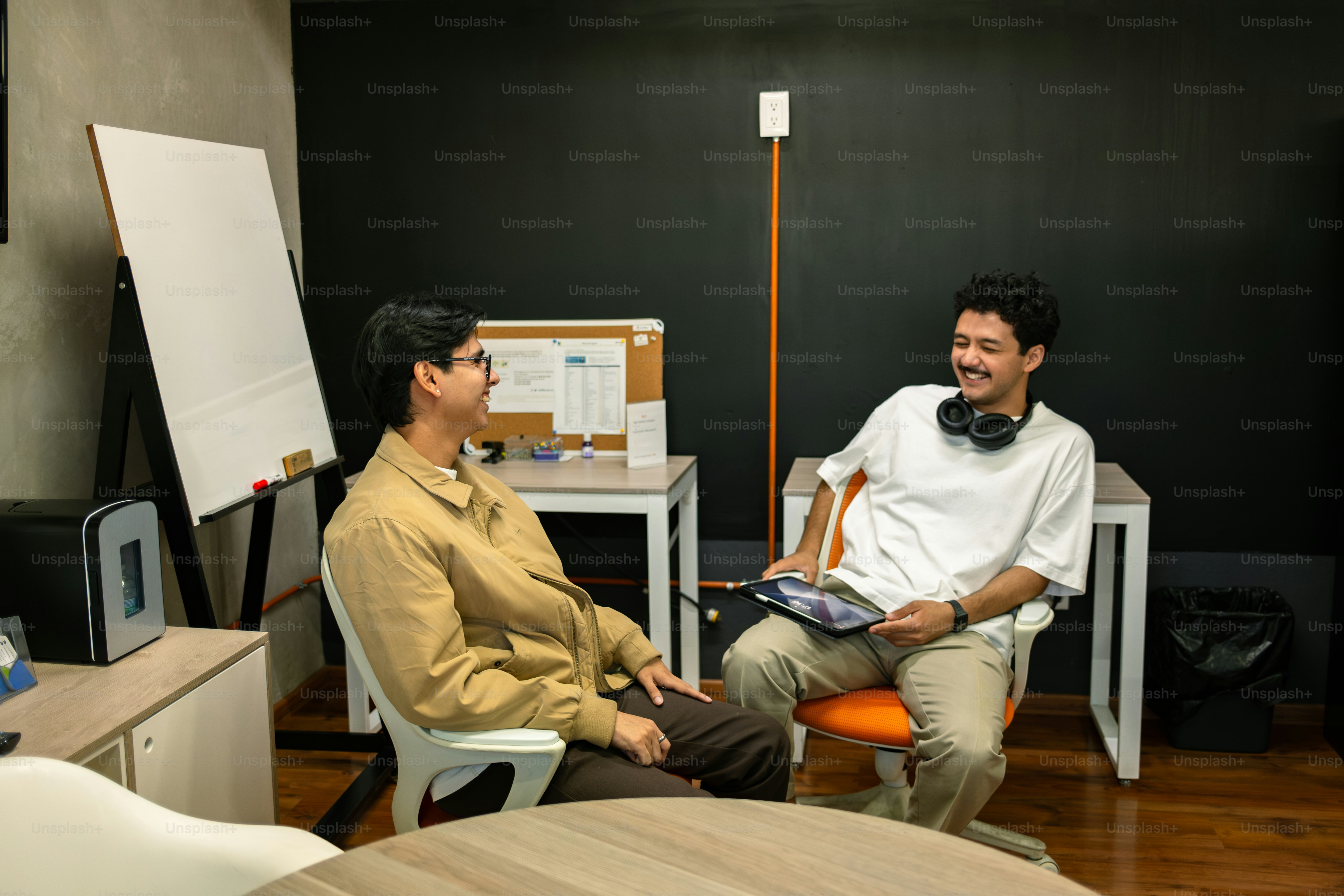 Two men converse in an office setting.