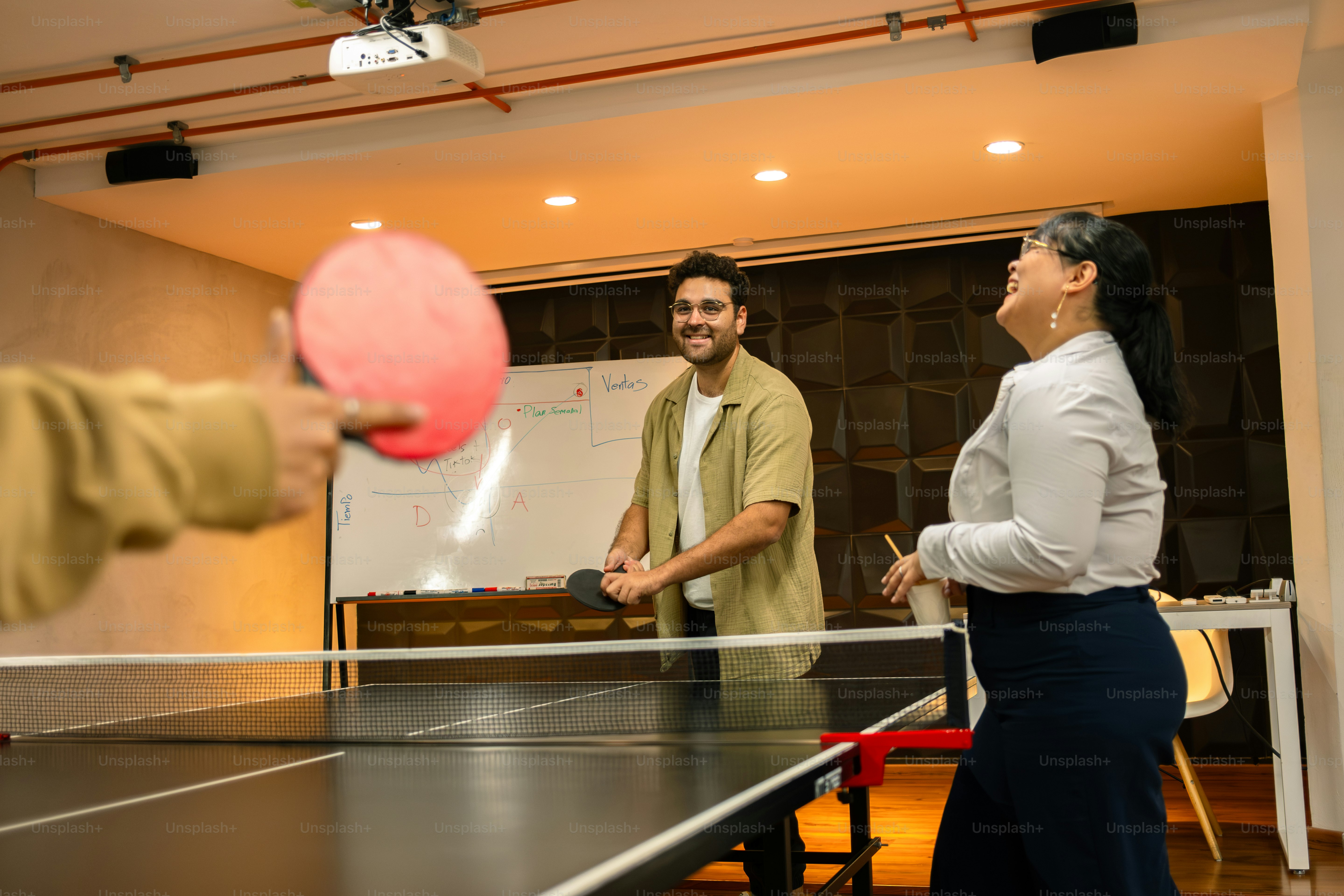 People are playing table tennis in an office.