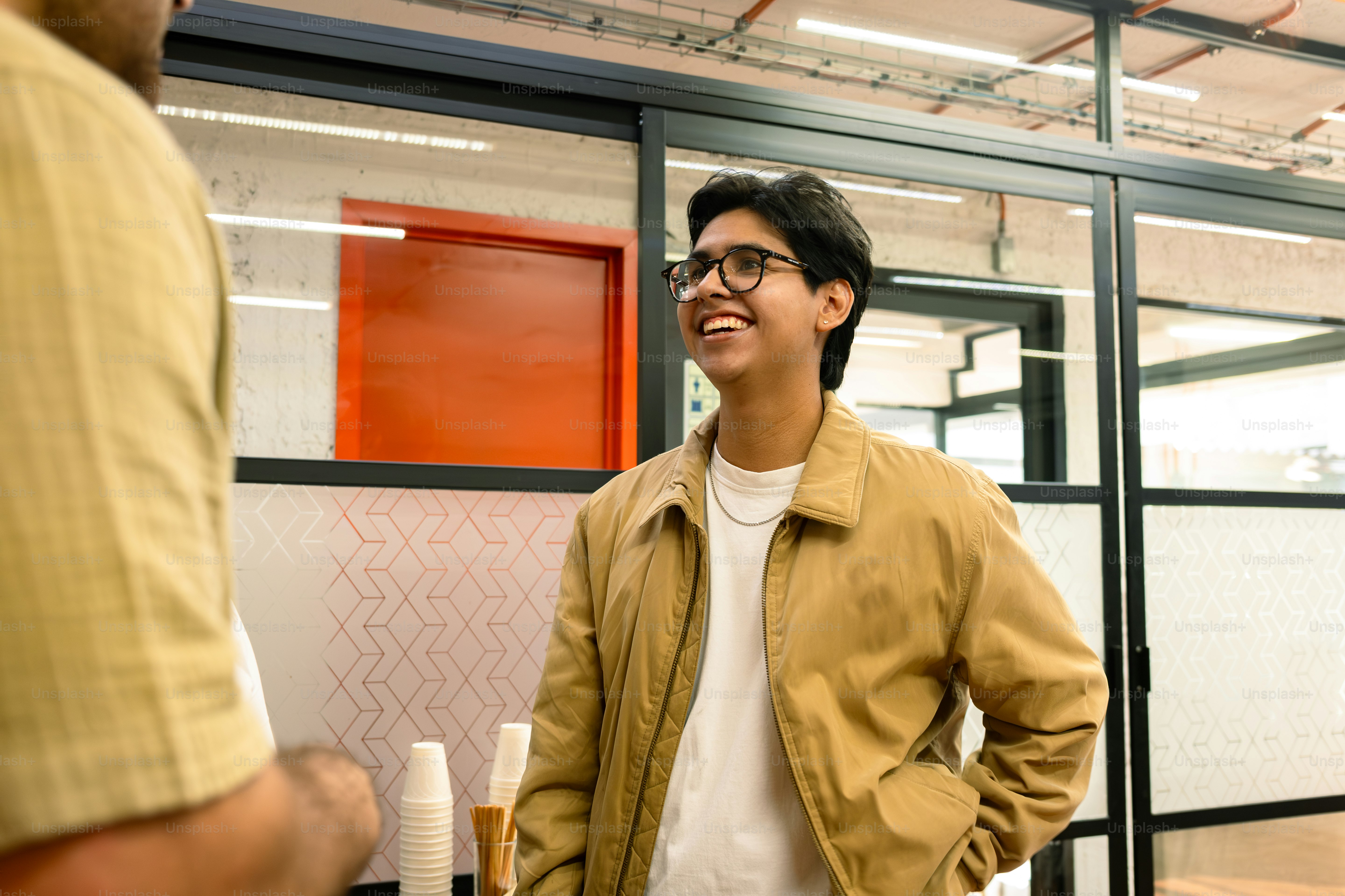 Smiling man chats with someone in an office.