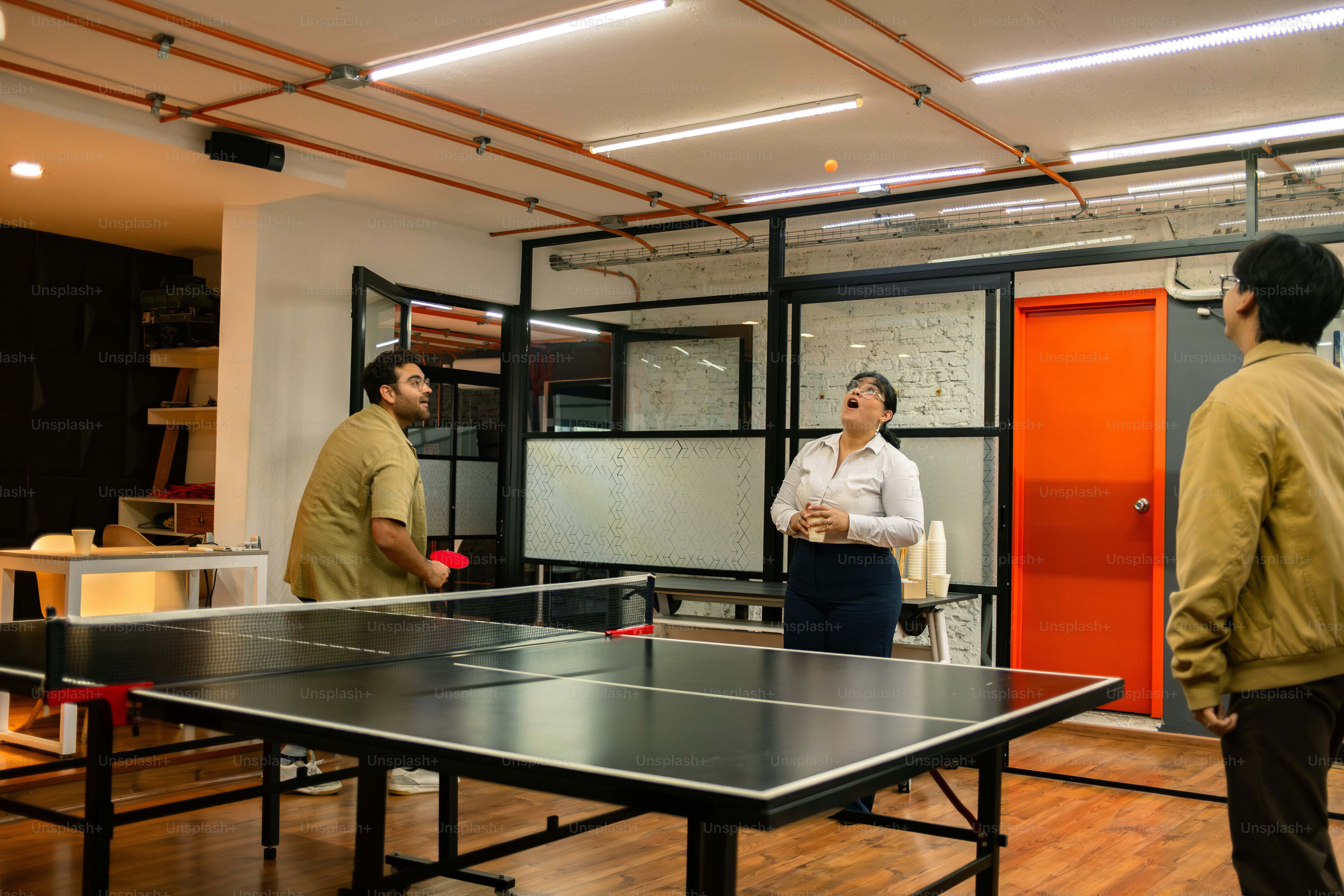 People are playing ping pong in an office space.
