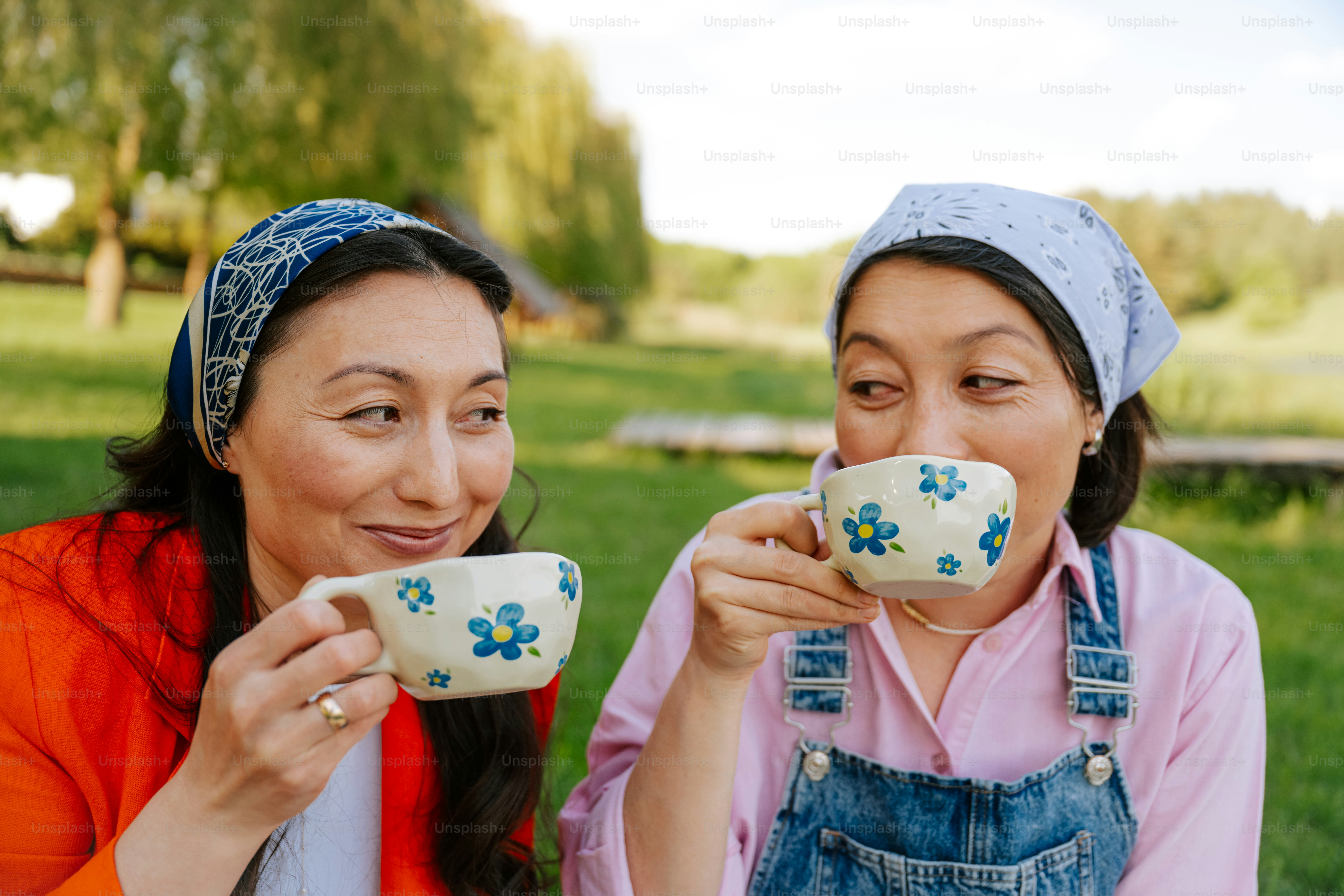 Two women enjoy tea outdoors on a sunny day.