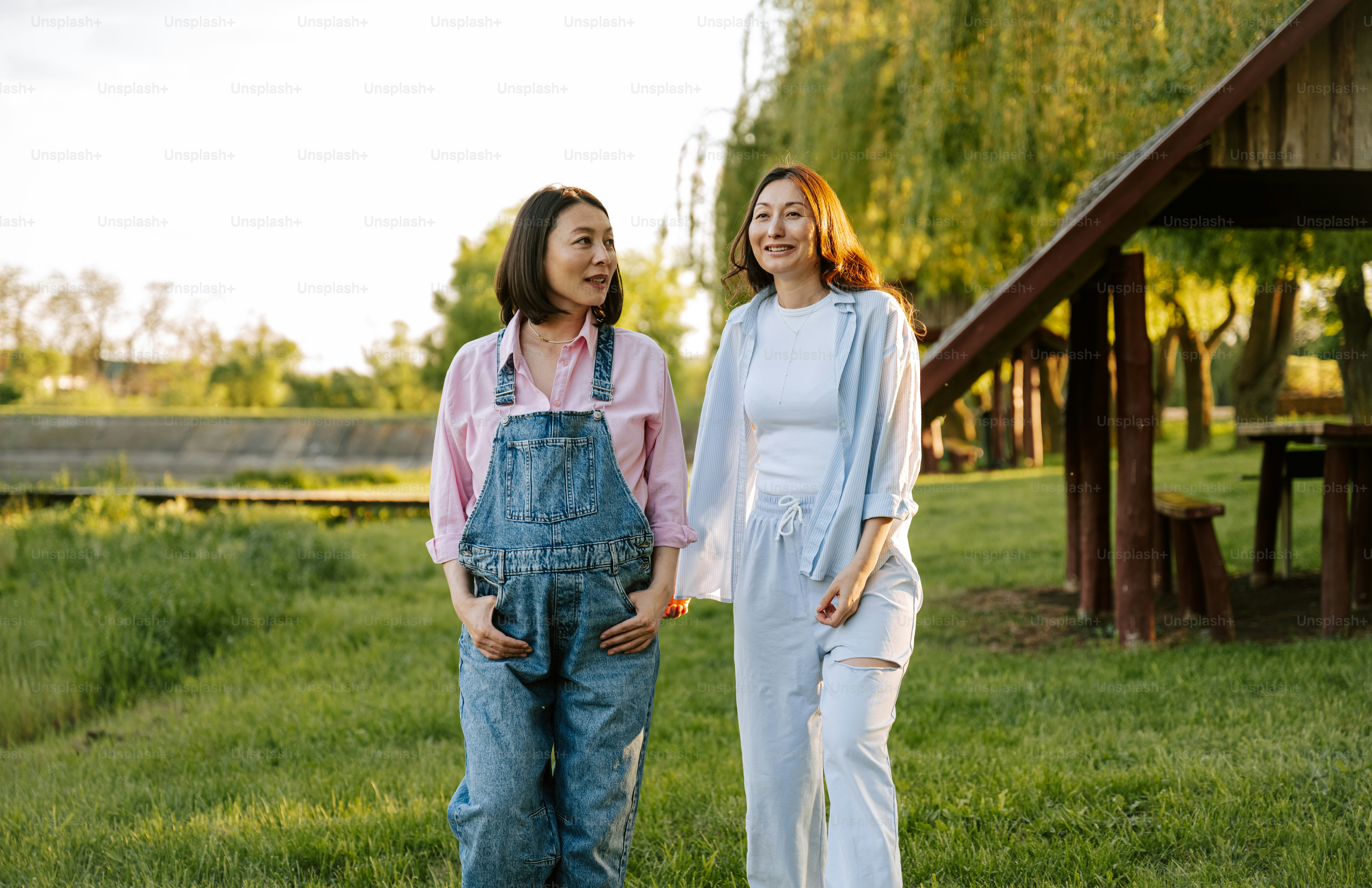 Two women walk together and smile in nature.
