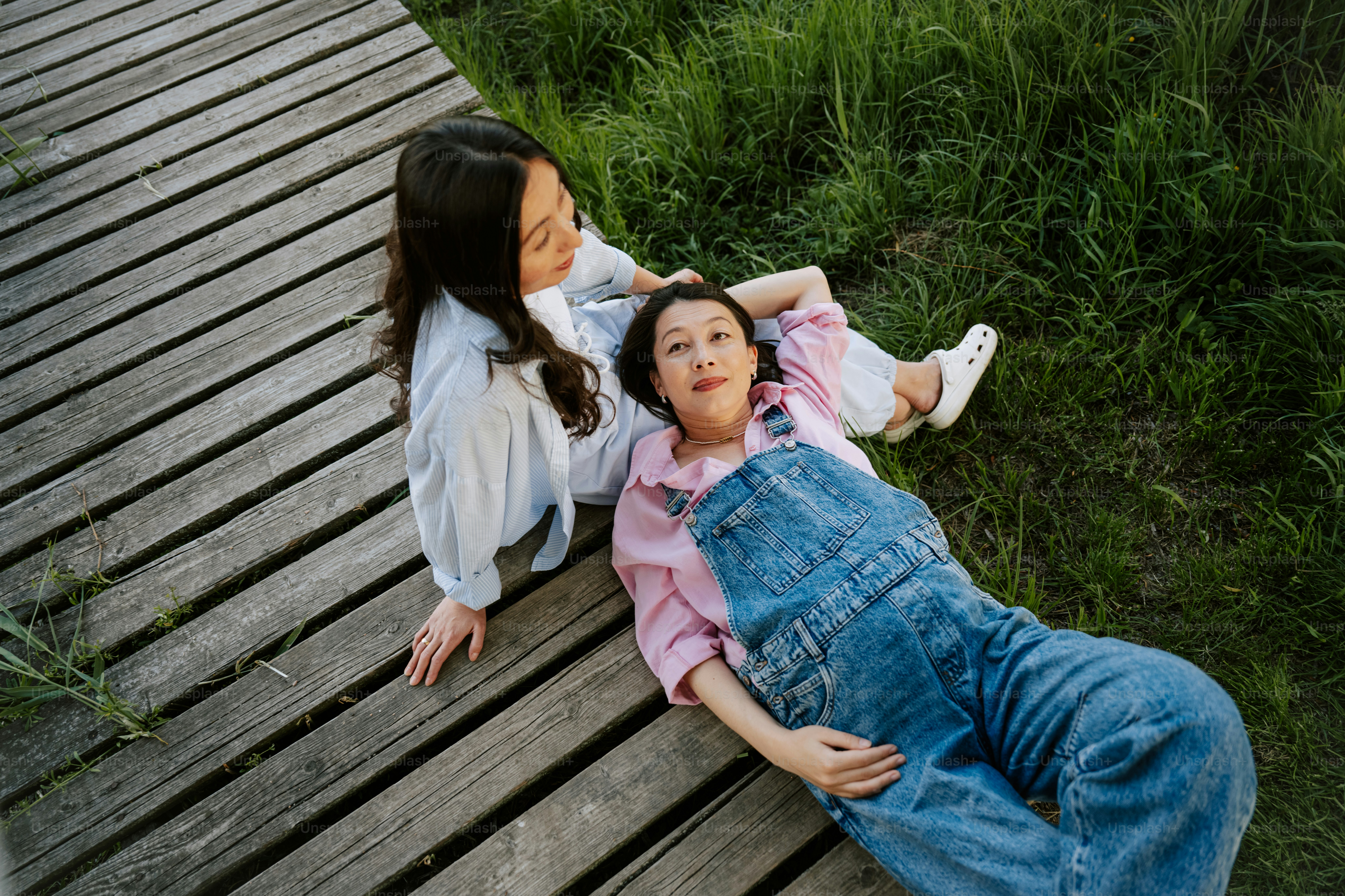 Two women relax together on a wooden deck.