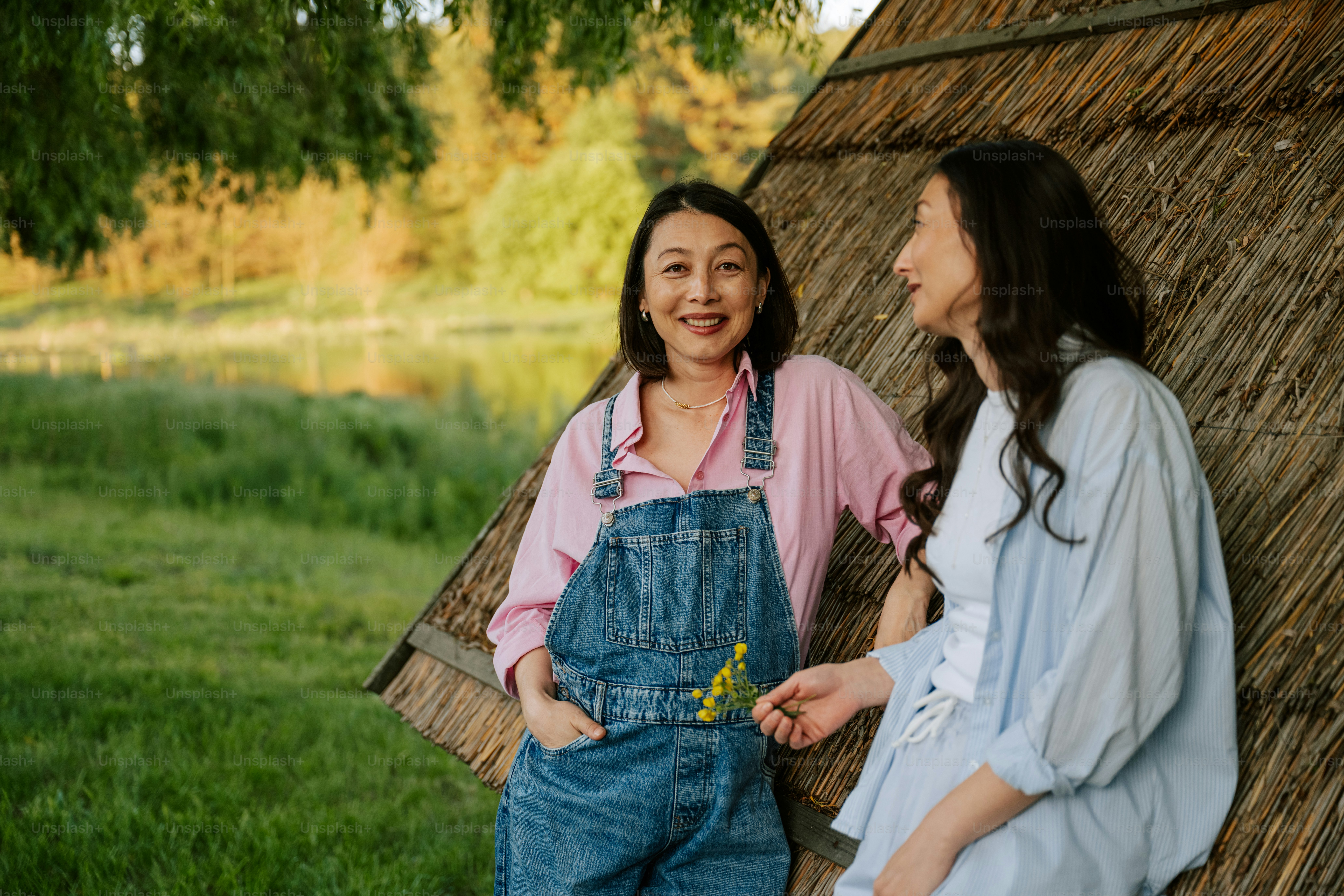 Two women are smiling and talking outdoors.