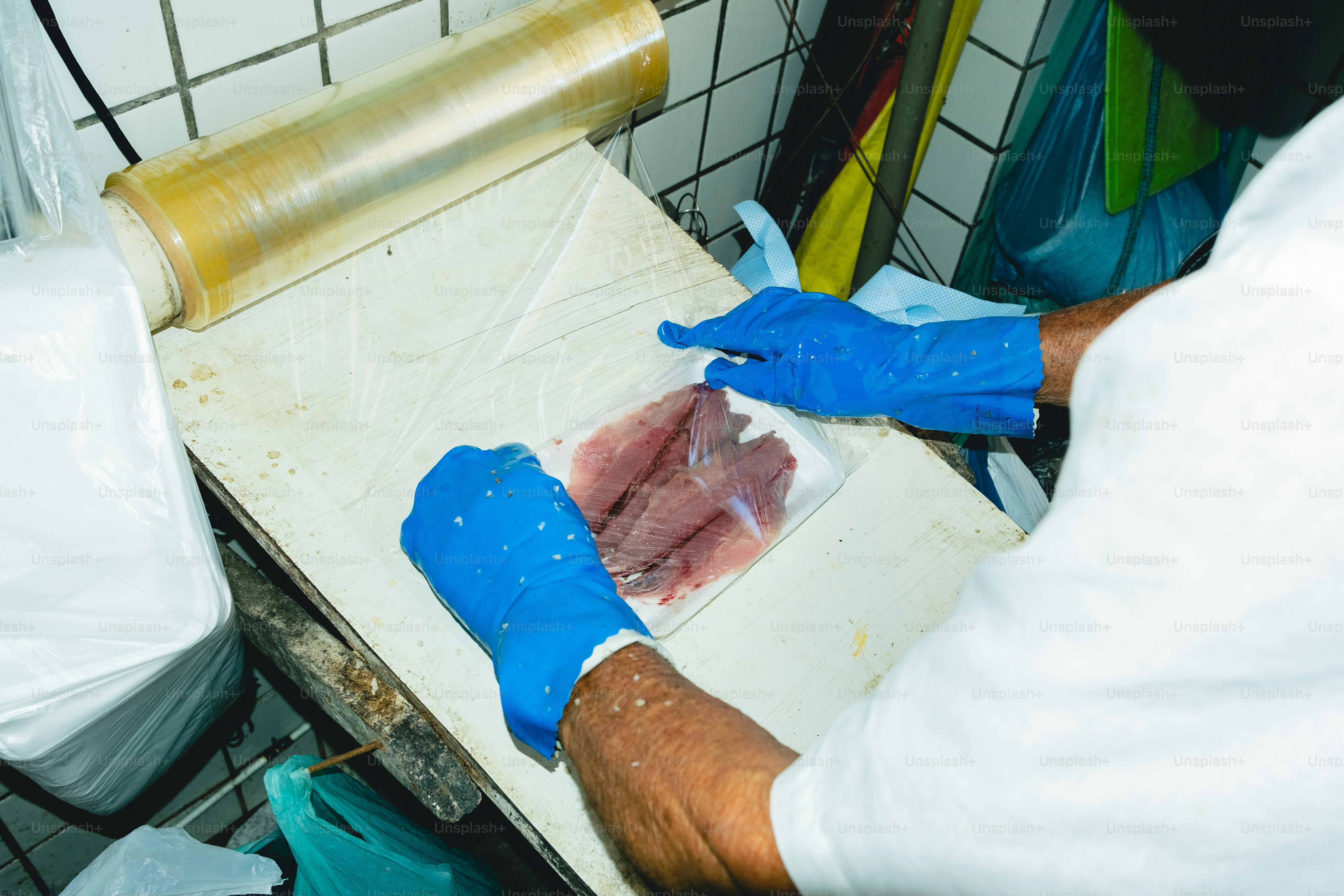 Someone is packaging raw fish with plastic wrap.