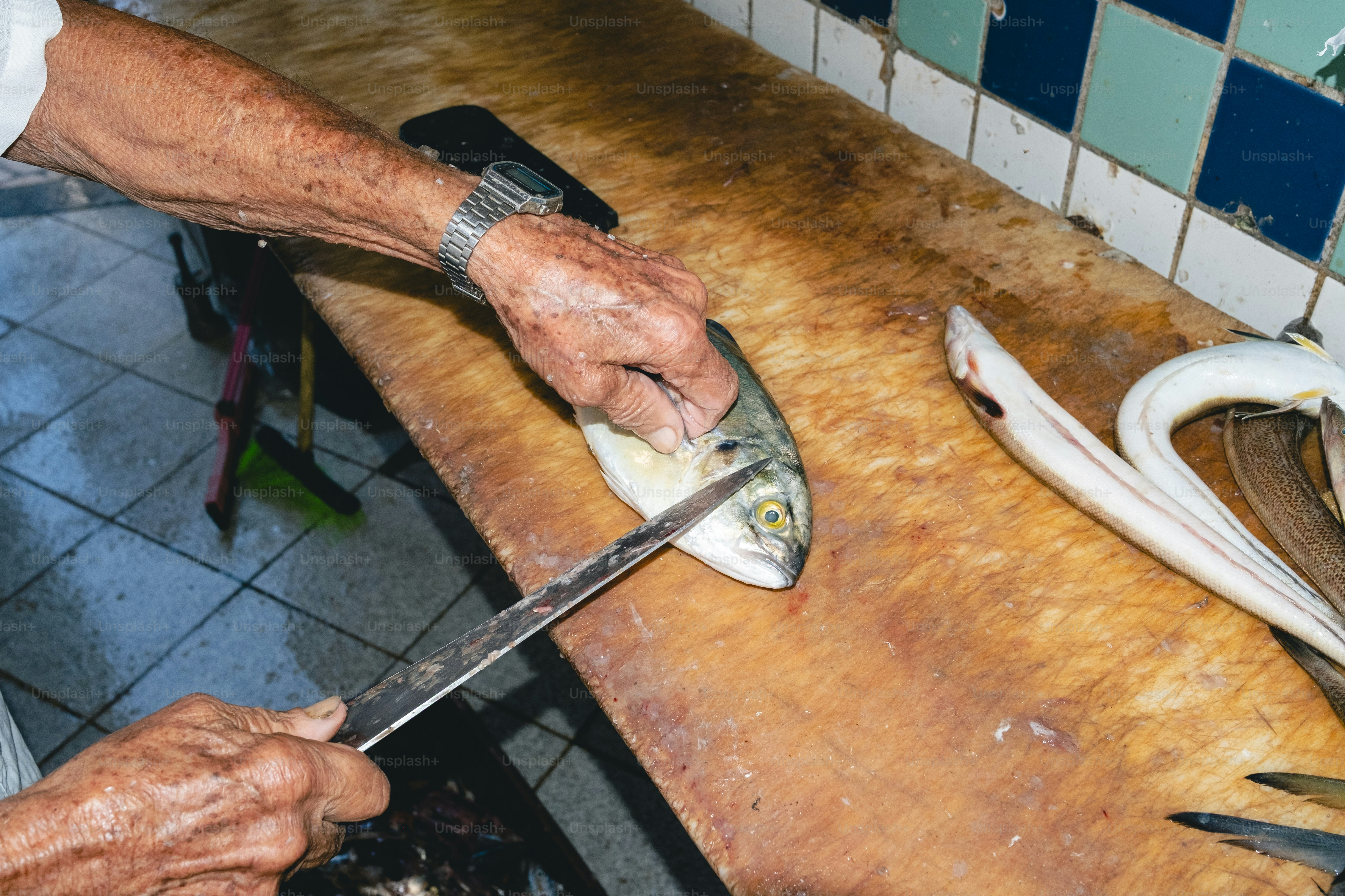 A hand is preparing fish on a wooden table.
