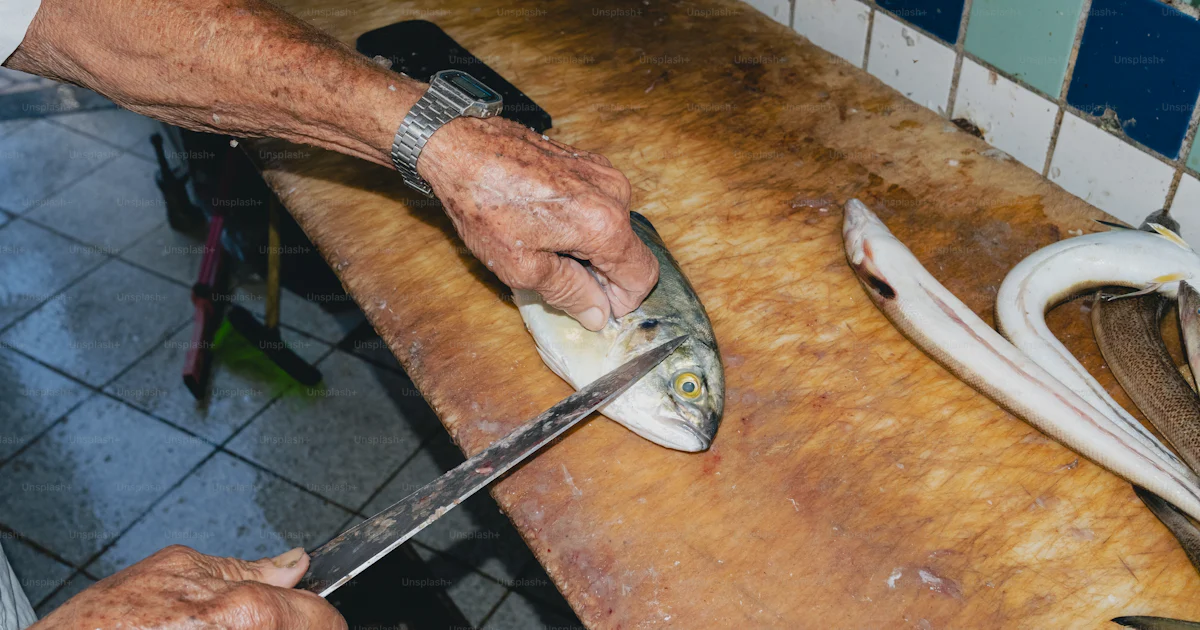 Fish On Table A hand is preparing fish on a wooden table. photo – Flash Image on Unsplash