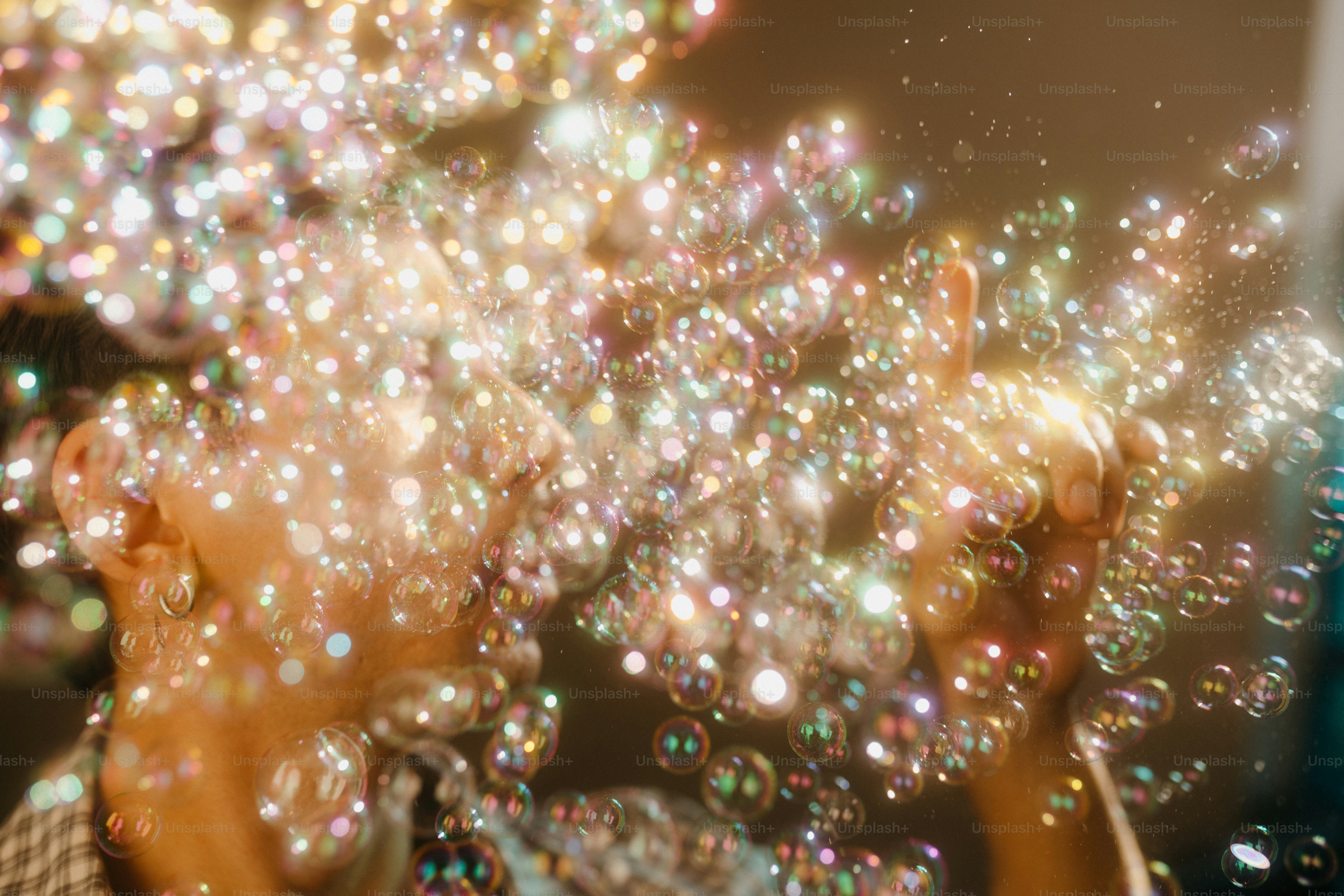 Someone is blowing a big stream of shimmering bubbles.