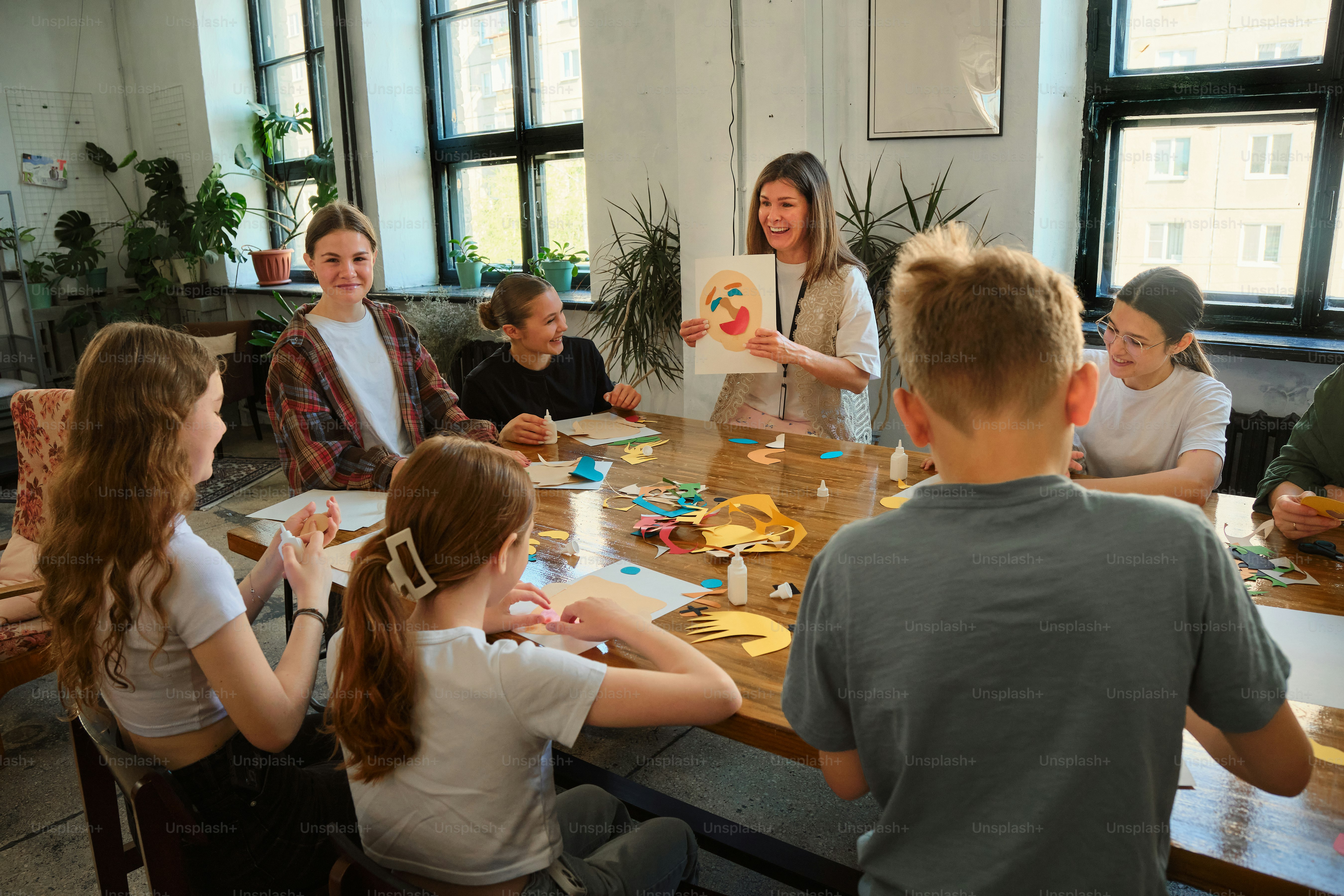 A teacher shows students their art project.