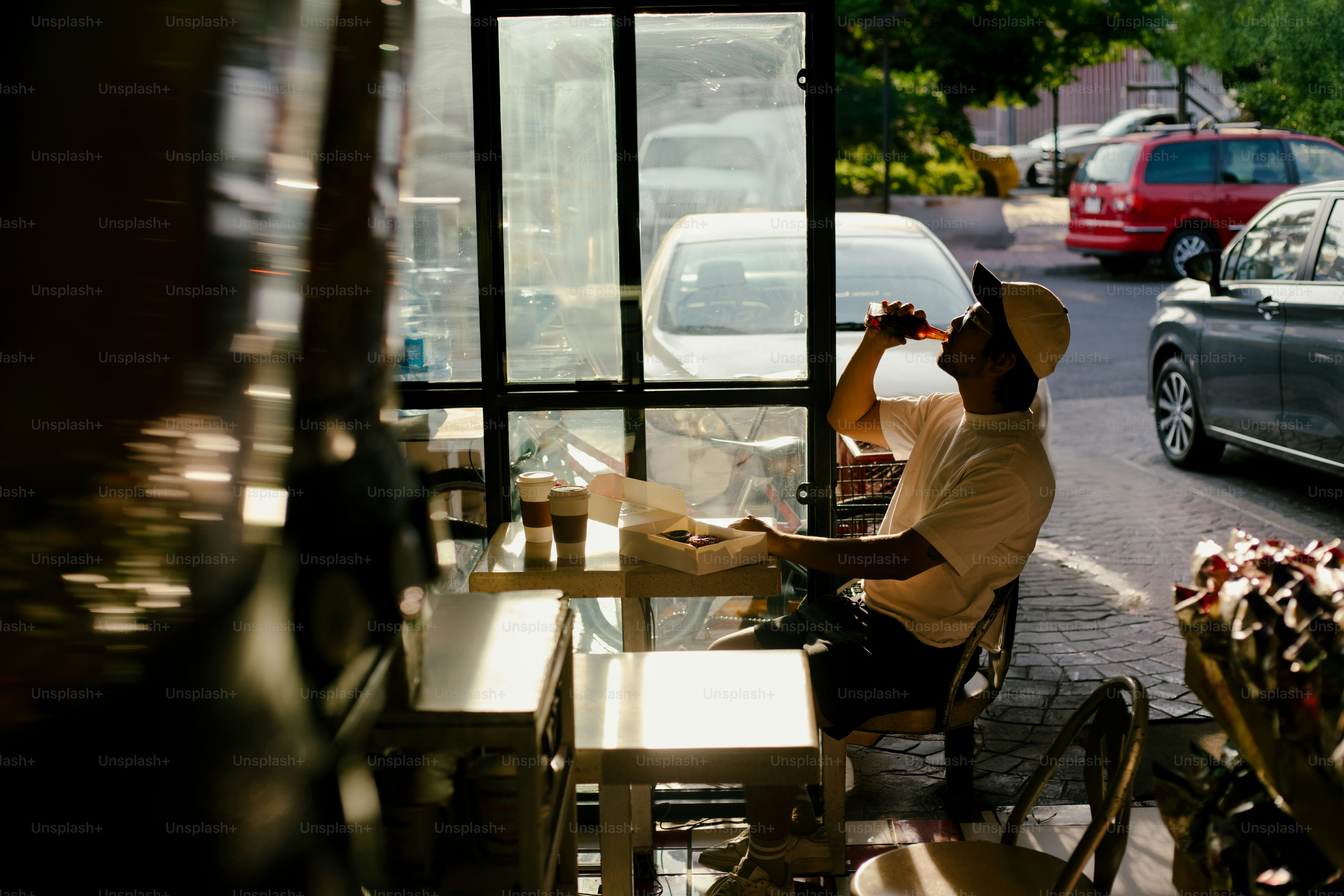 A man drinks inside a cafe, by the window.