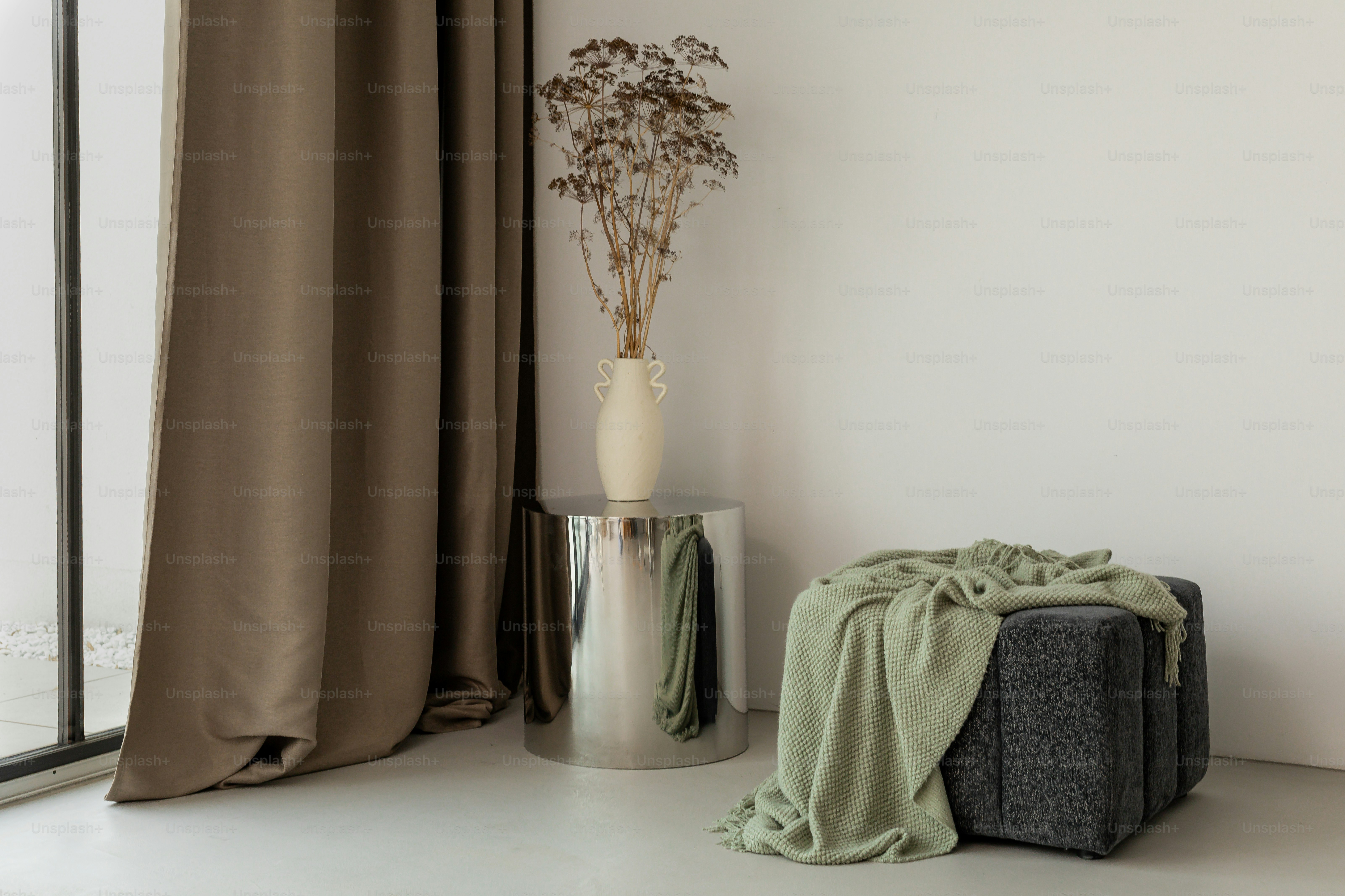 Elegant room decor: curtains, vase, and ottoman.