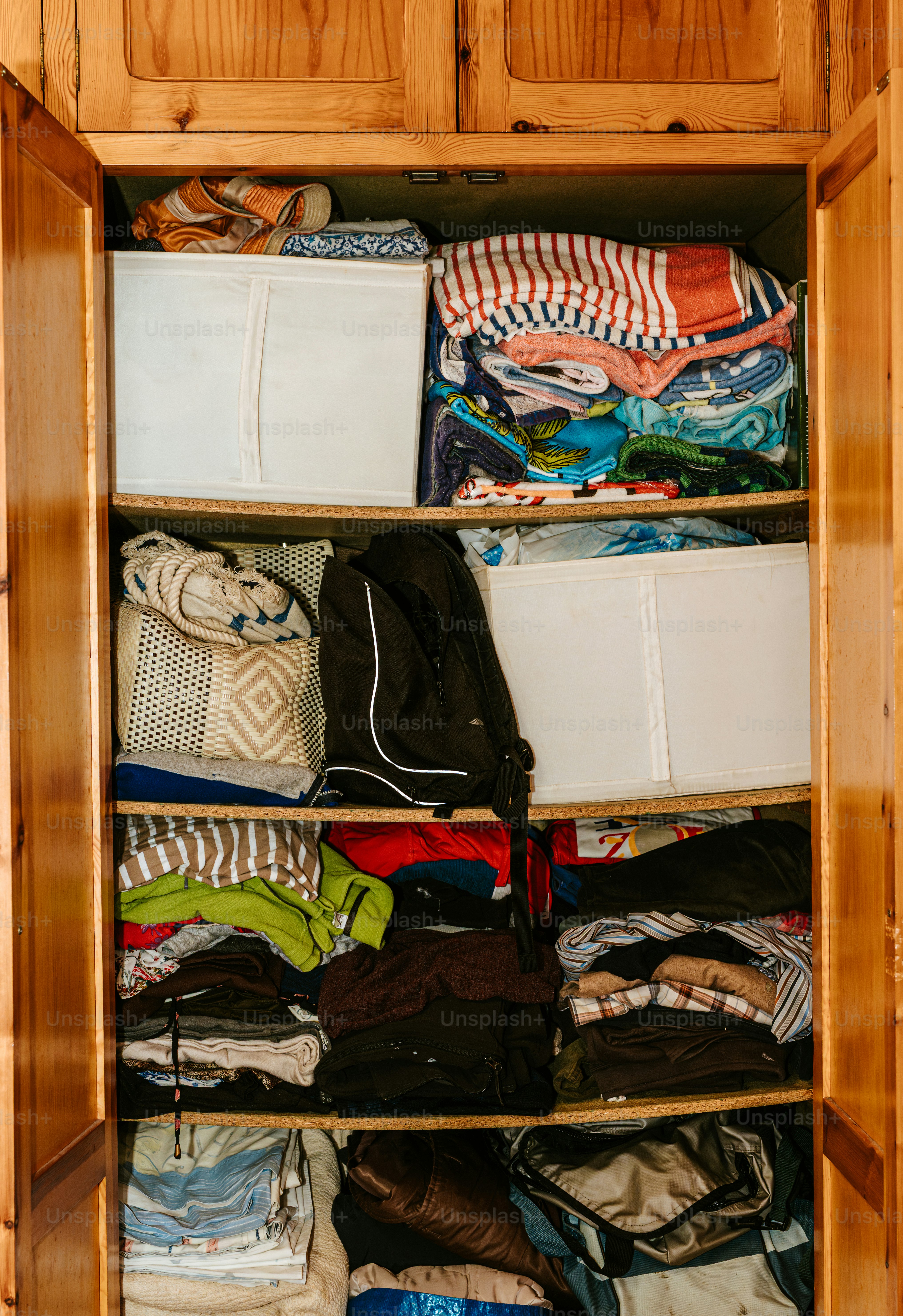 An open wardrobe is filled with clothes and bags.