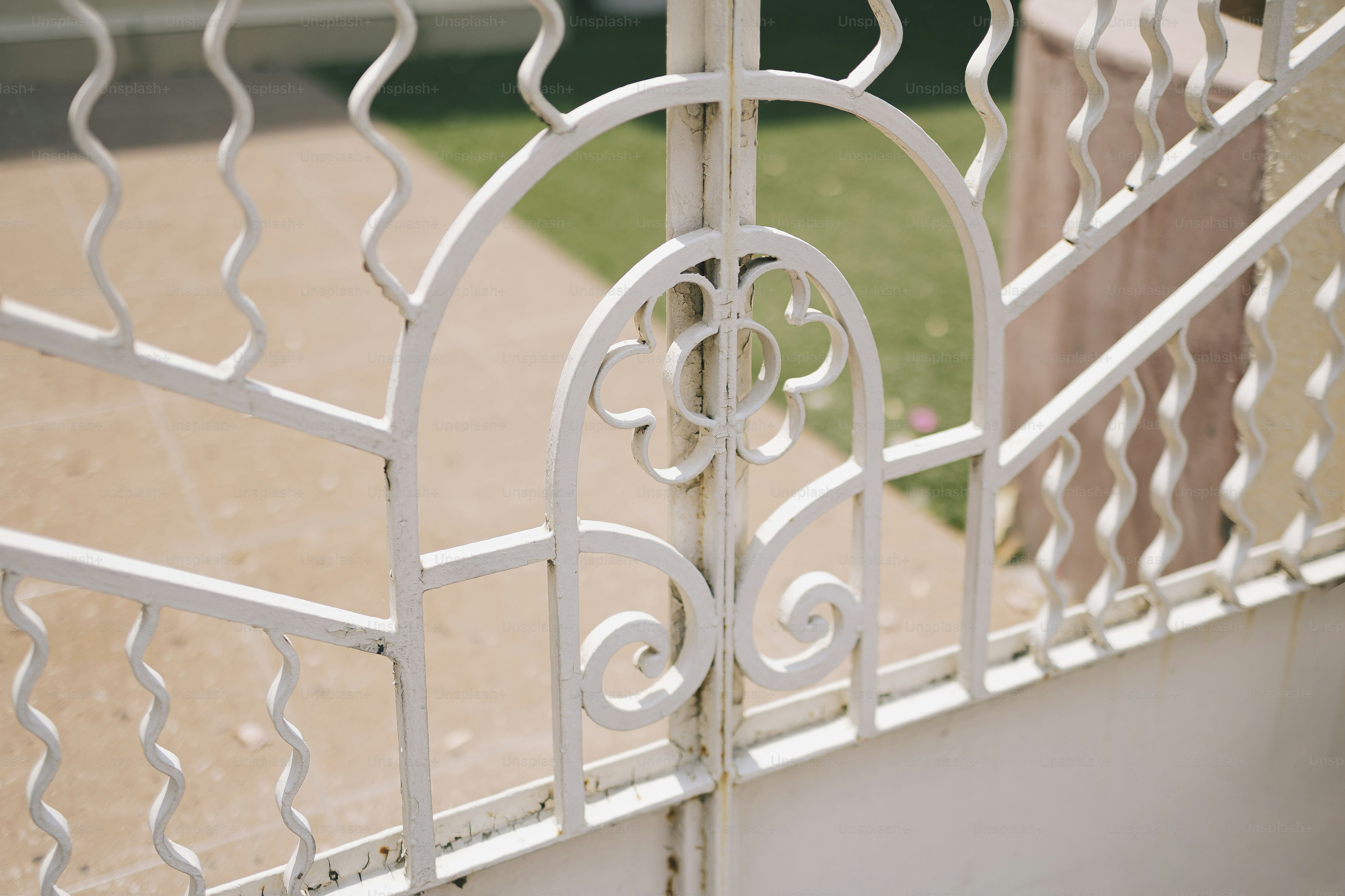Recinzione metallica decorativa bianca con motivo floreale.