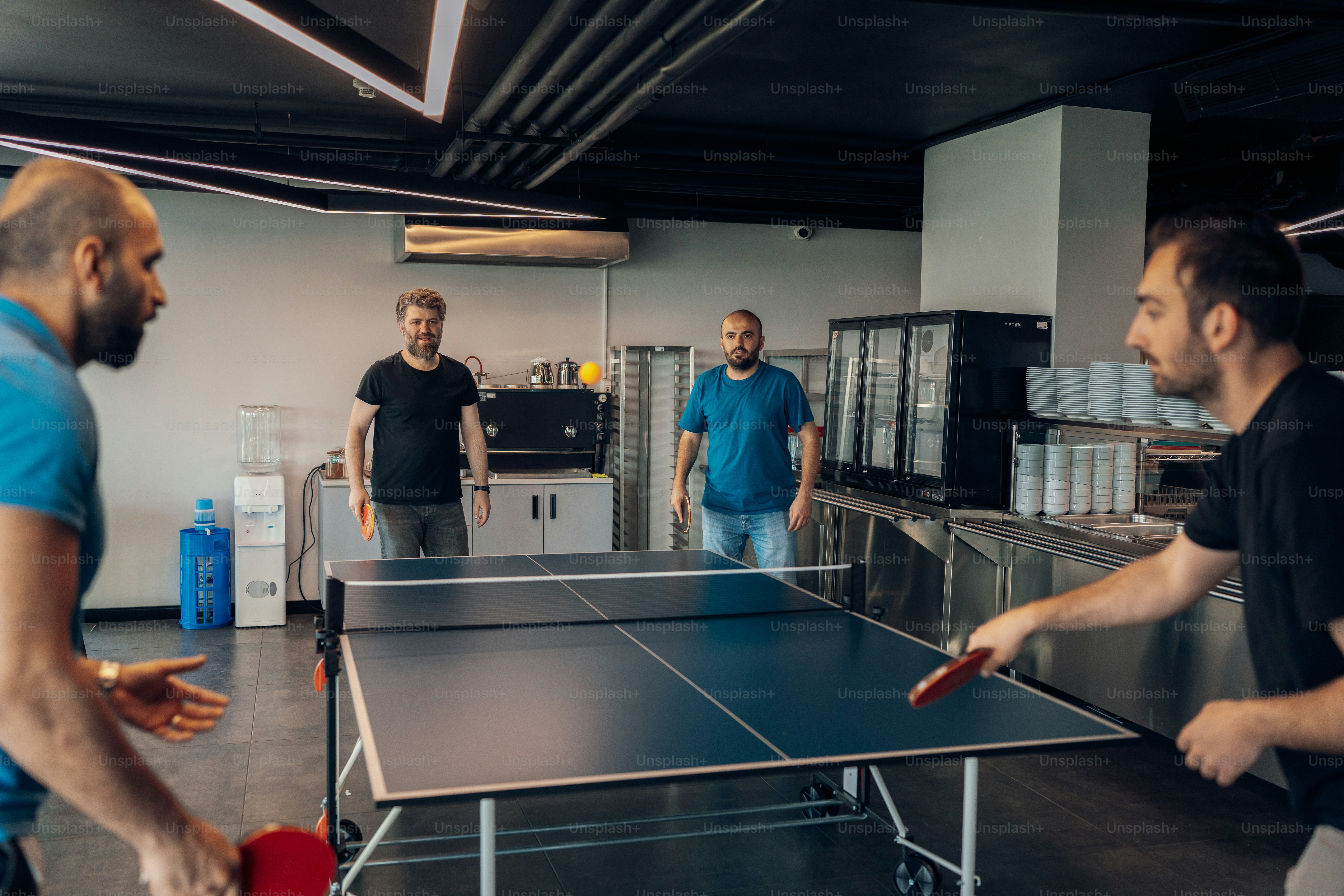 Homens estão jogando pingue-pongue em um escritório.