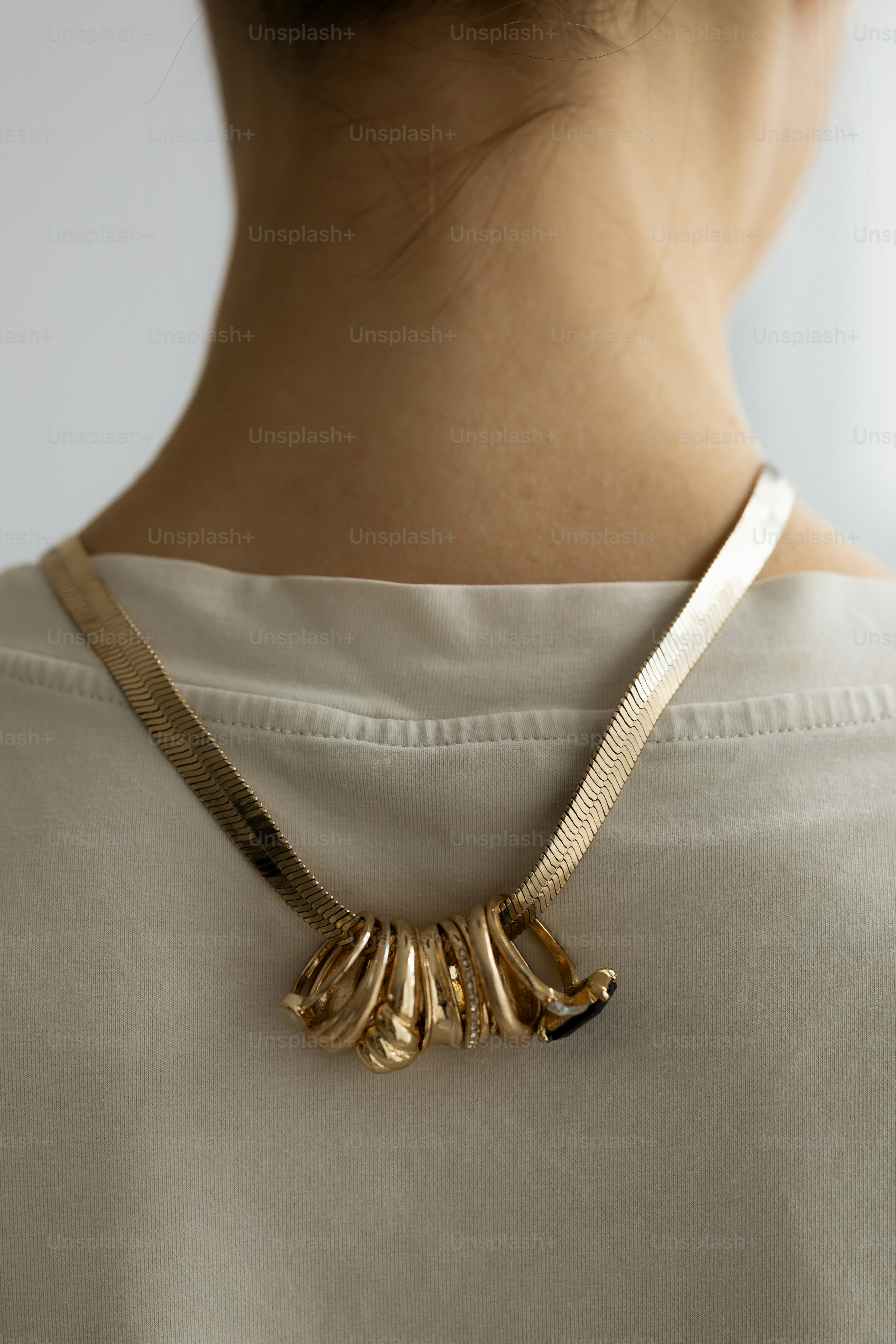 A woman wears a unique gold necklace.