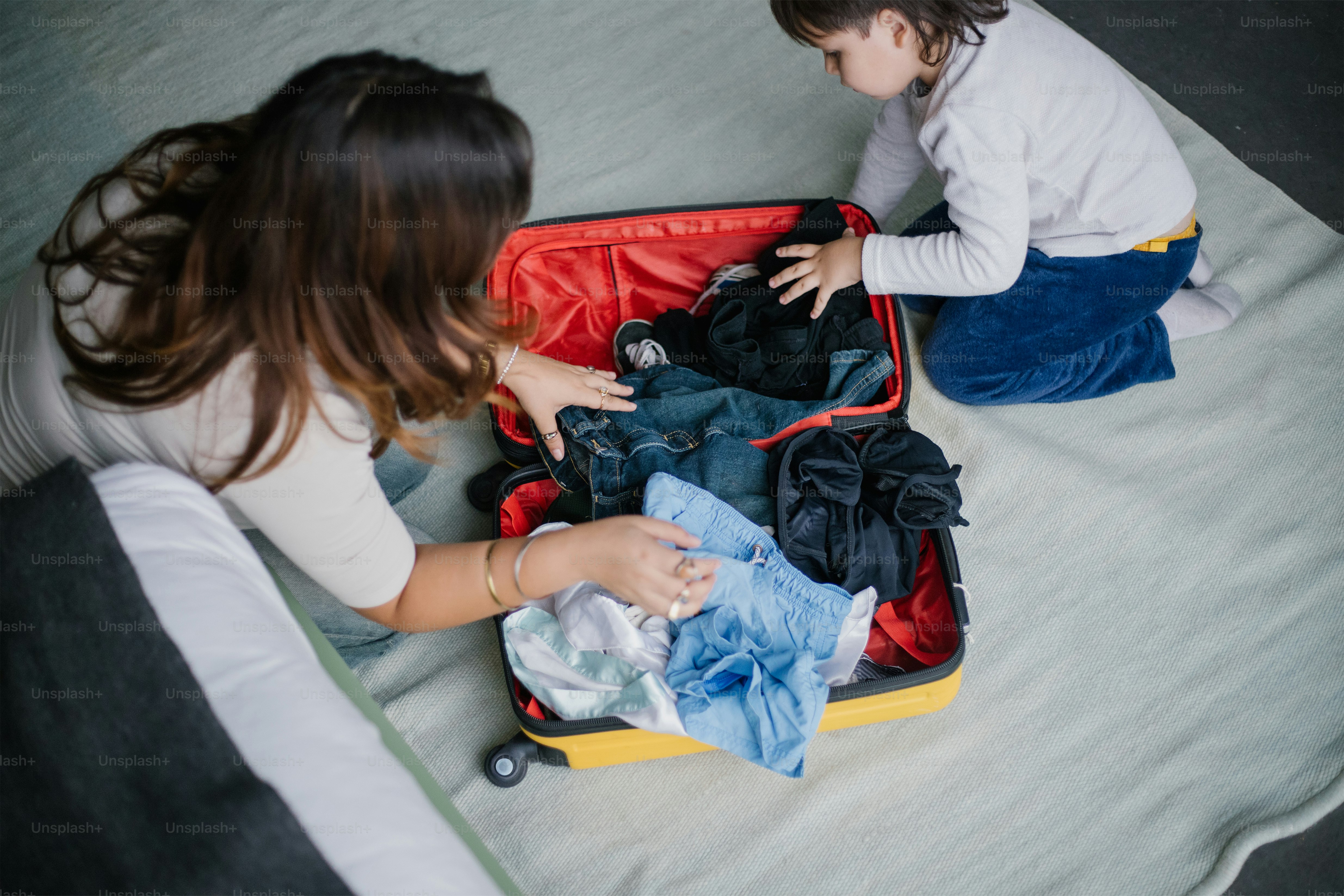 Mother and child pack a suitcase together.