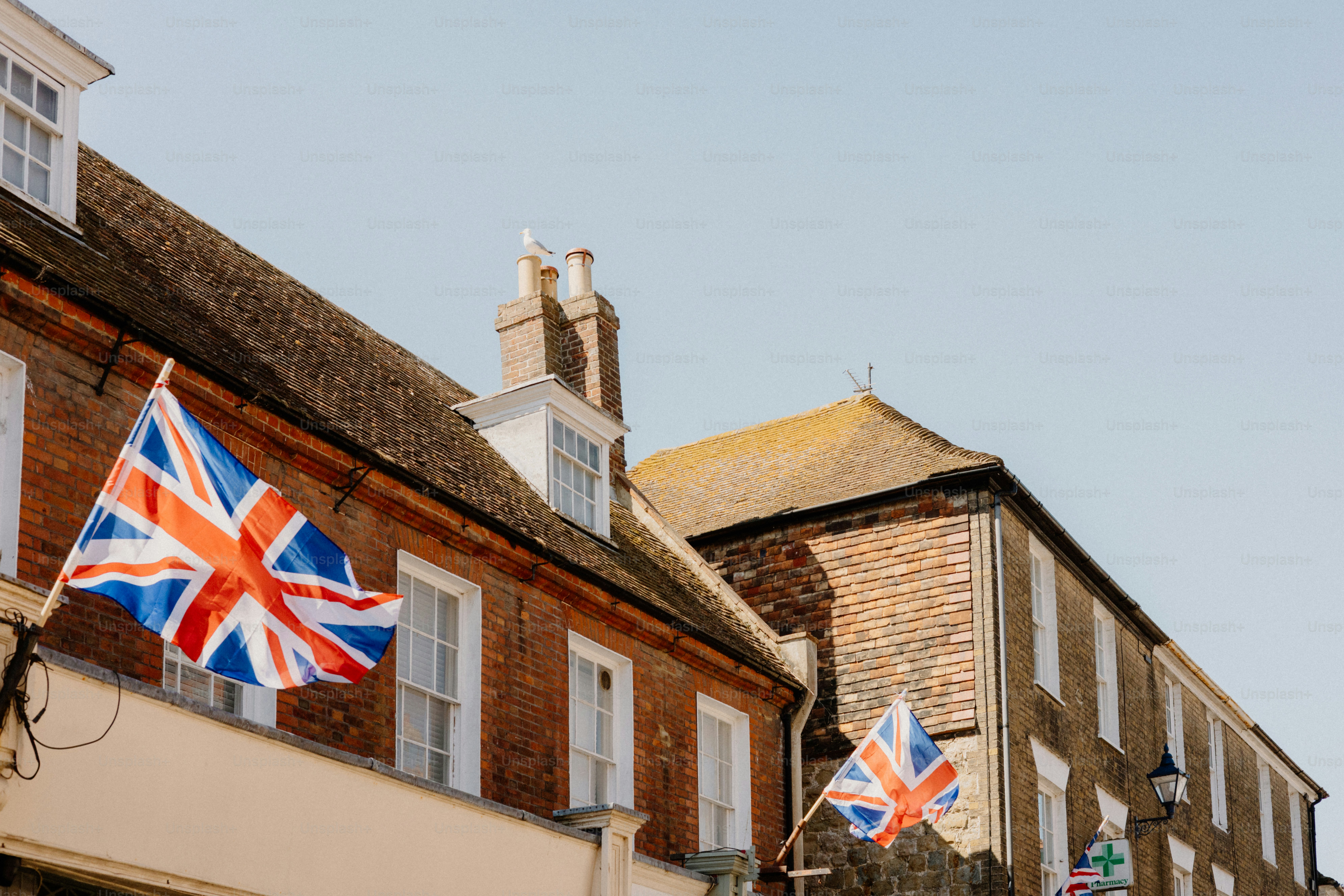 British flags hang on buildings in the sun.