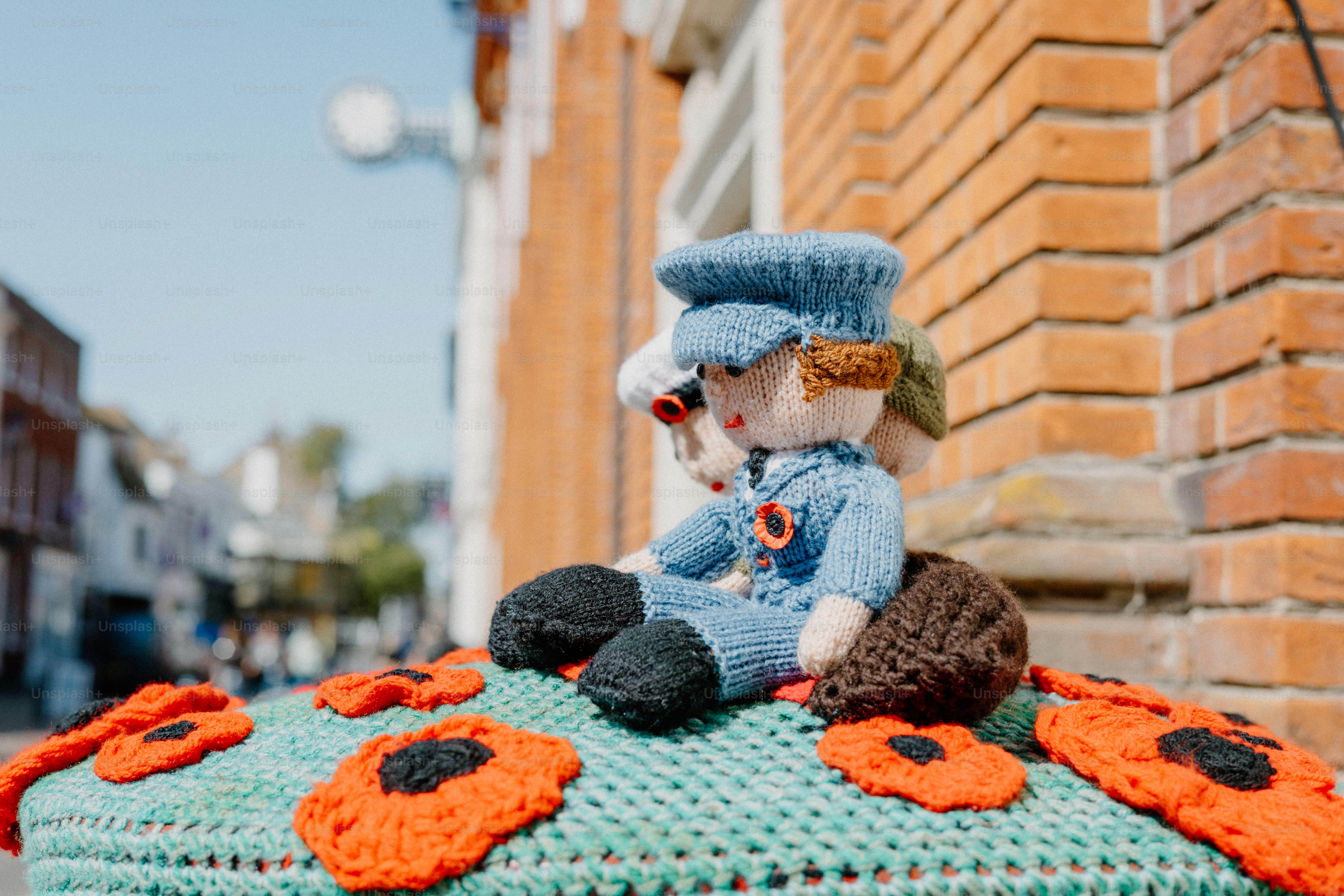 Des figurines tricotées et des coquelicots décorent une exposition extérieure.